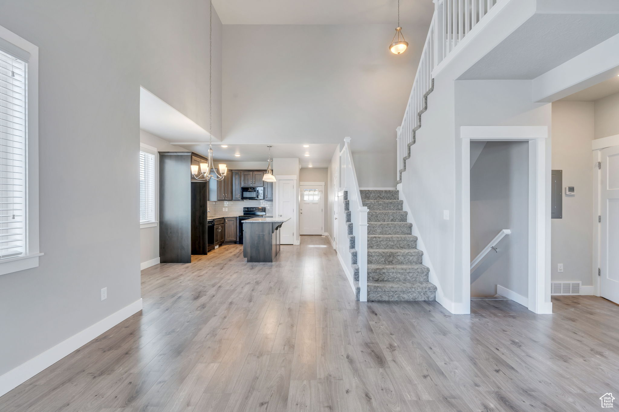 Living room with a notable chandelier, a high ceiling, and light hardwood / wood-style flooring