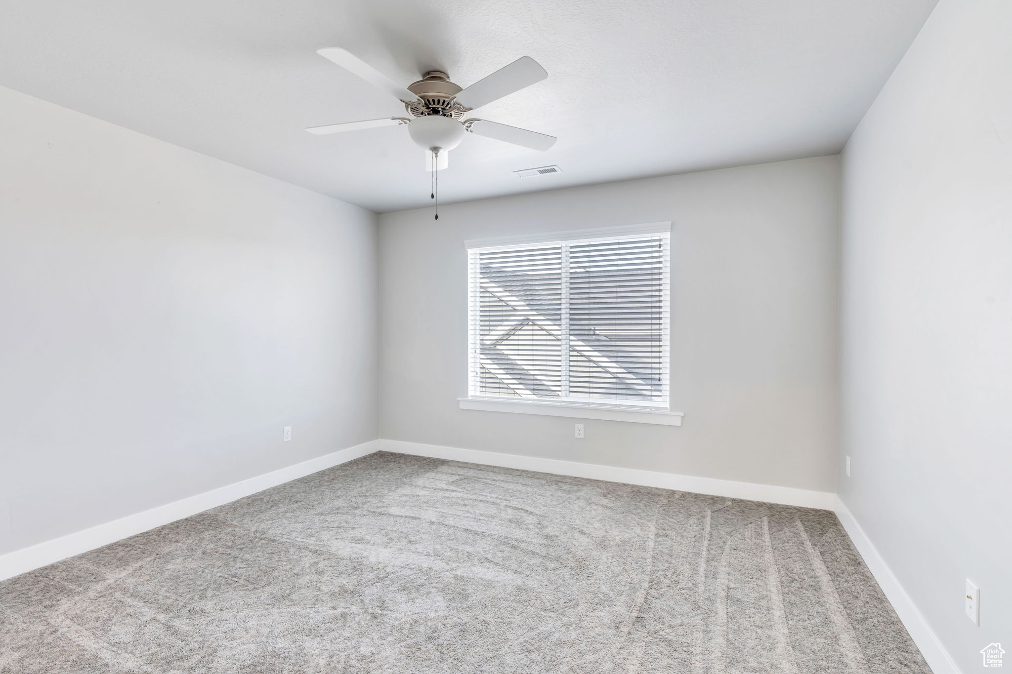 Carpeted spare room with ceiling fan