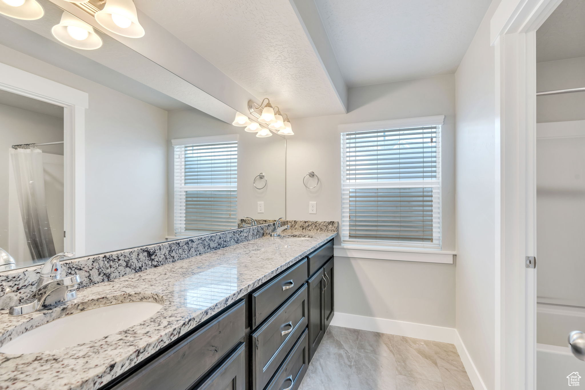 Bathroom with a chandelier, vanity, walk in shower, and a healthy amount of sunlight