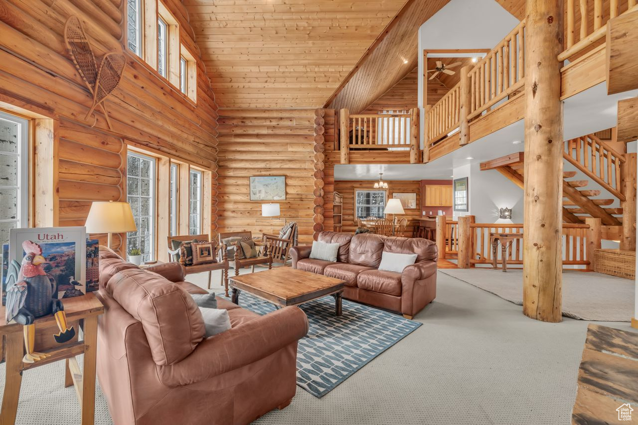 Living room featuring wooden ceiling, light carpet, high vaulted ceiling, ceiling fan, and rustic walls