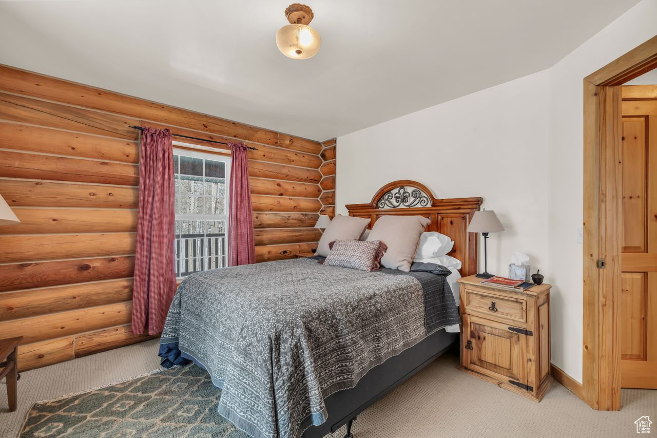 Carpeted bedroom featuring rustic walls