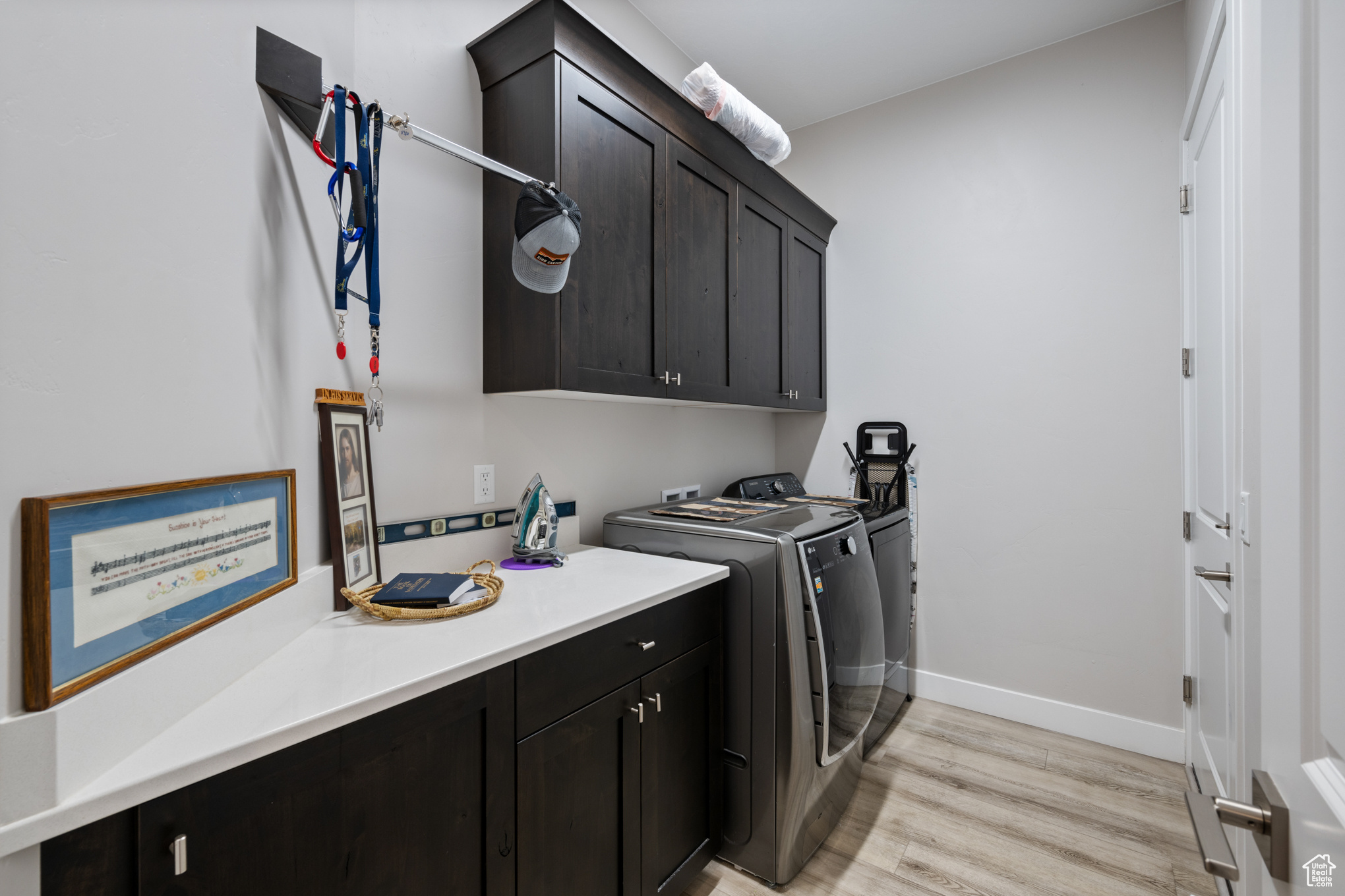 Washroom with cabinets, light wood-type flooring, and washing machine and dryer