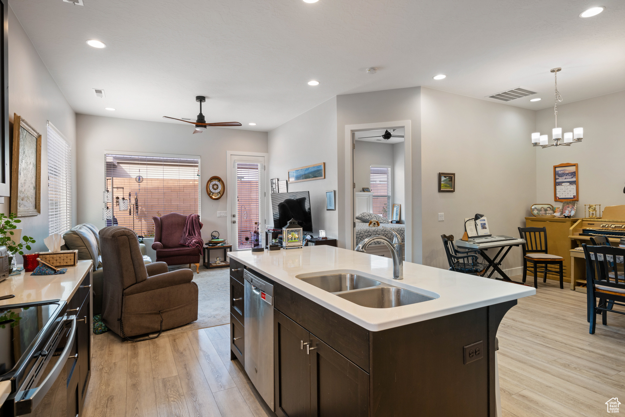Kitchen featuring sink, decorative light fixtures, light hardwood / wood-style flooring, dishwasher, and an island with sink