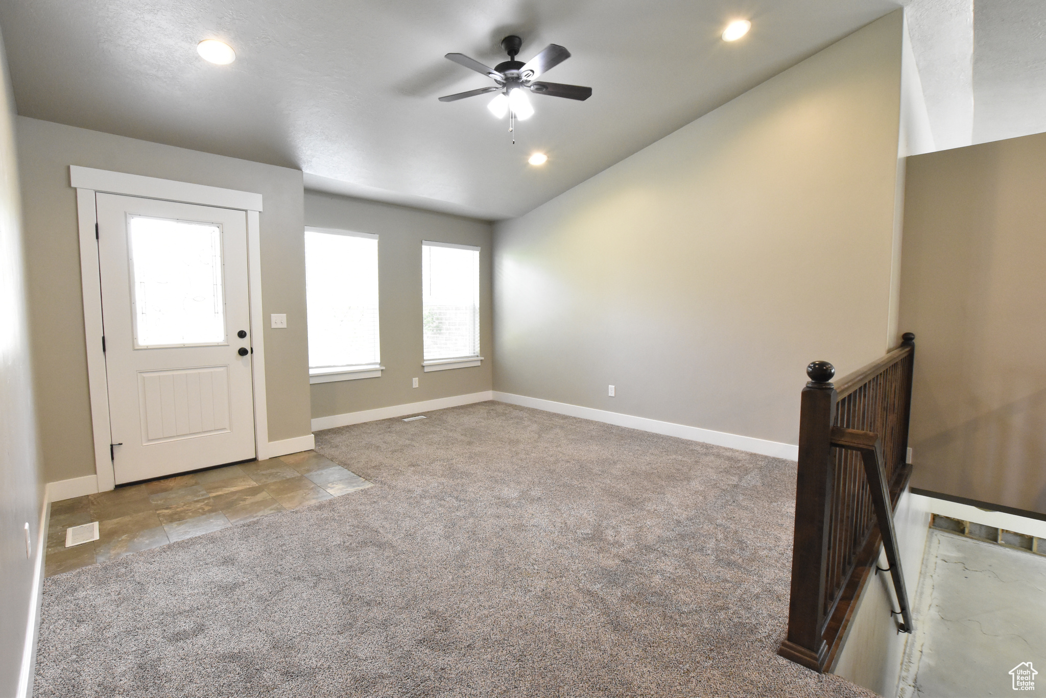 Interior space featuring ceiling fan, light colored carpet, and lofted ceiling