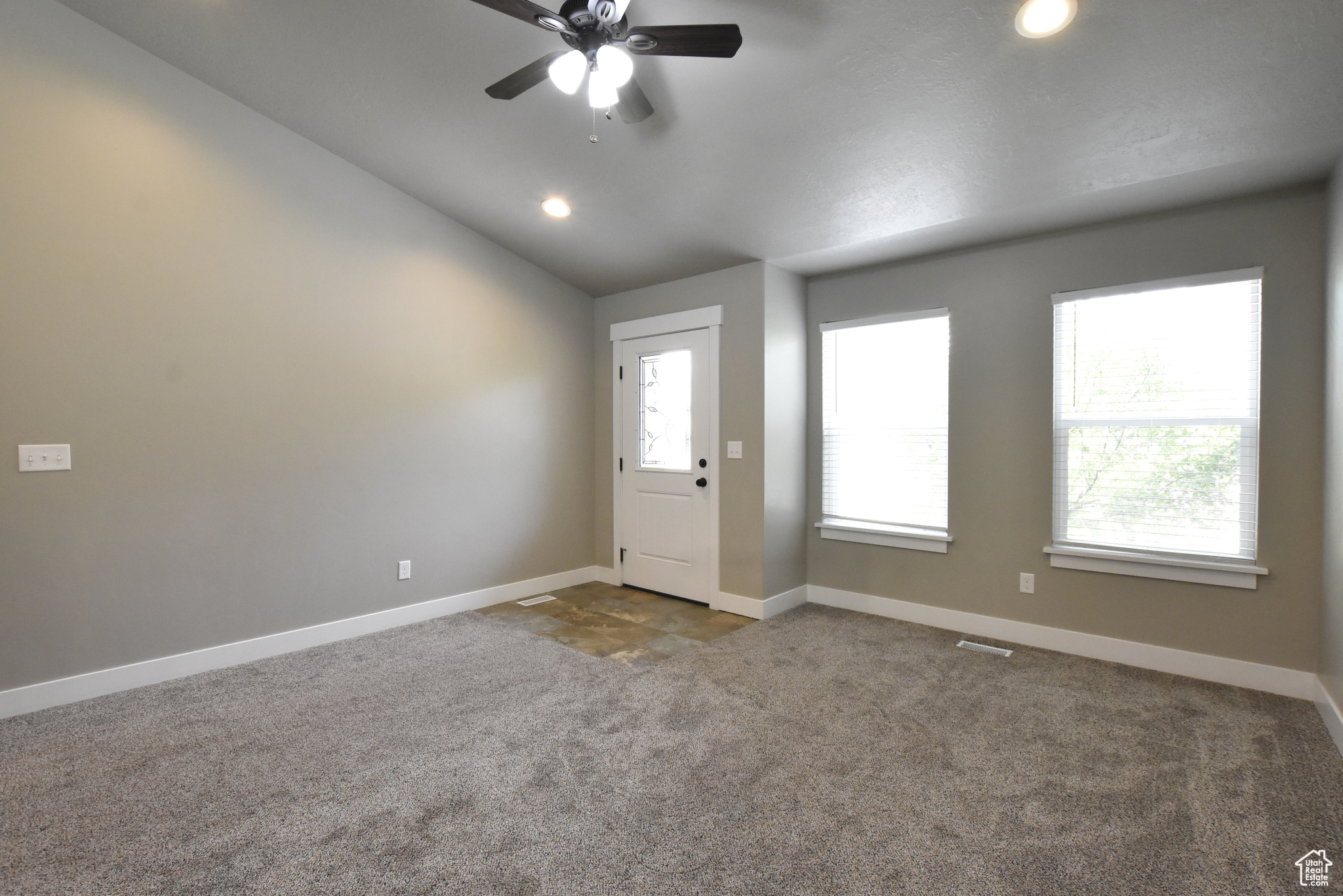 Entrance foyer featuring plenty of natural light, ceiling fan, lofted ceiling, and carpet floors