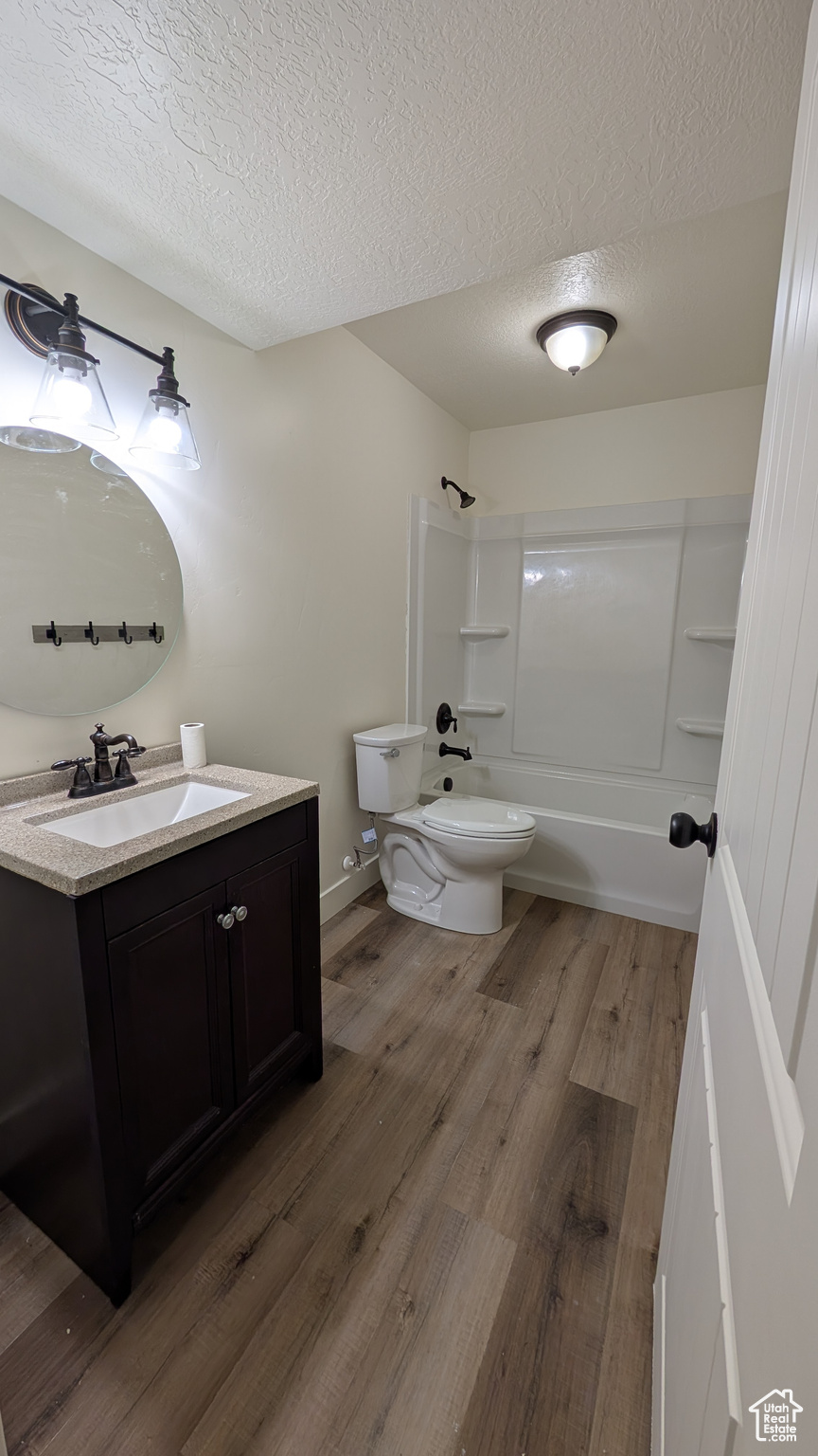 Full bathroom featuring vanity, wood-type flooring, toilet, a textured ceiling, and shower / bath combination