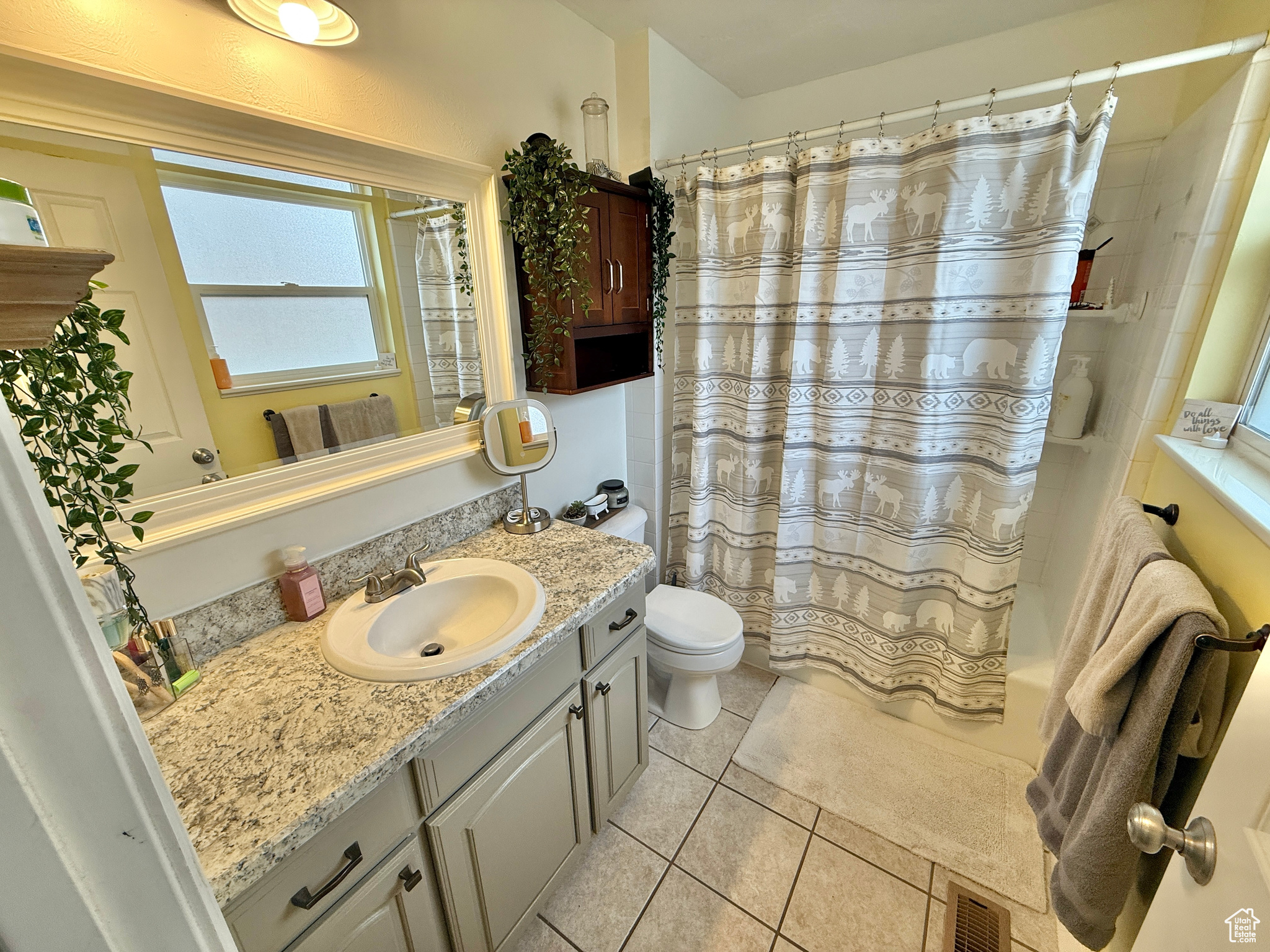 Full bathroom with tile patterned flooring, vanity, toilet, and shower / bath combo with shower curtain