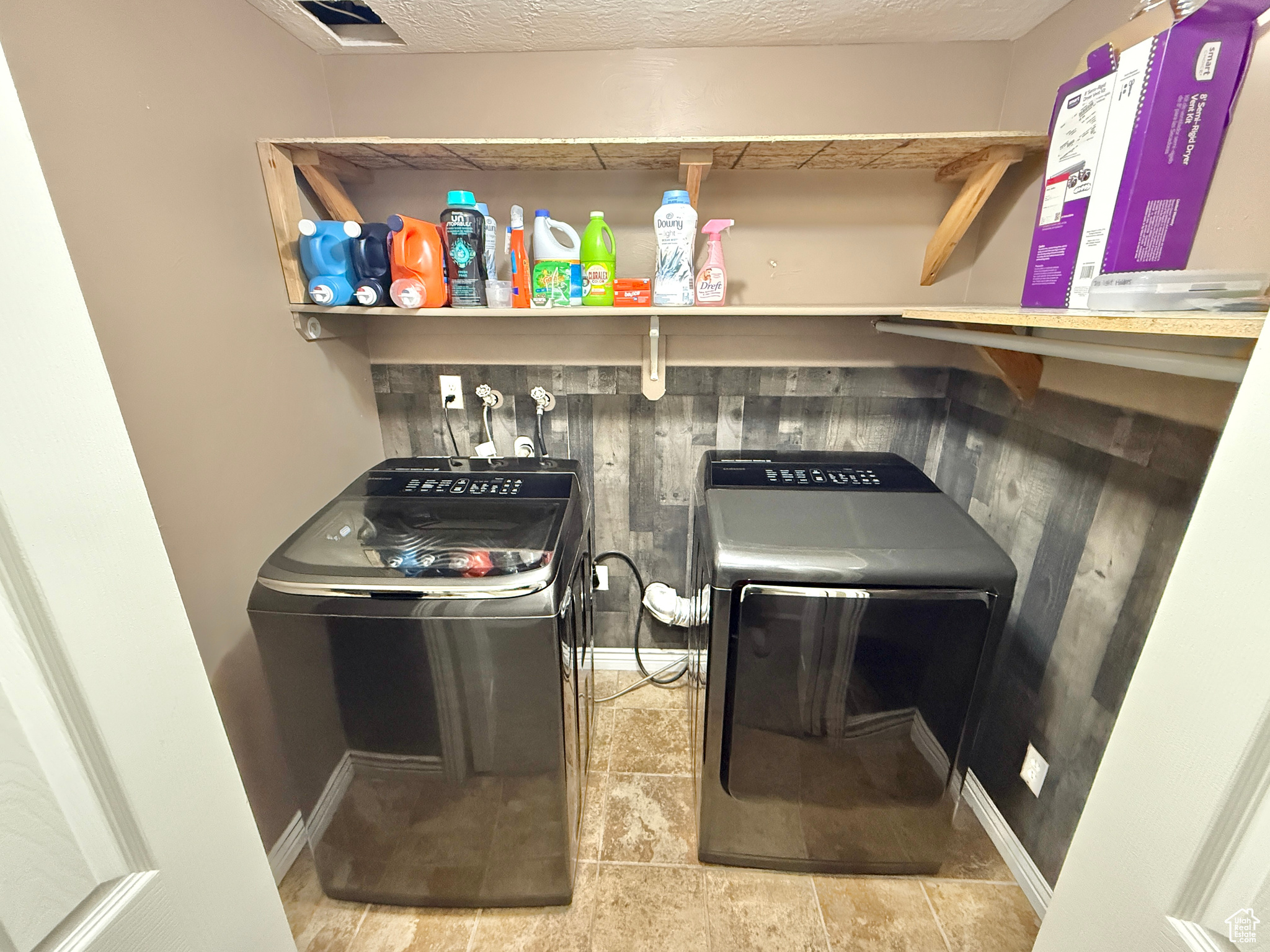 Laundry room with a textured ceiling and washer and clothes dryer