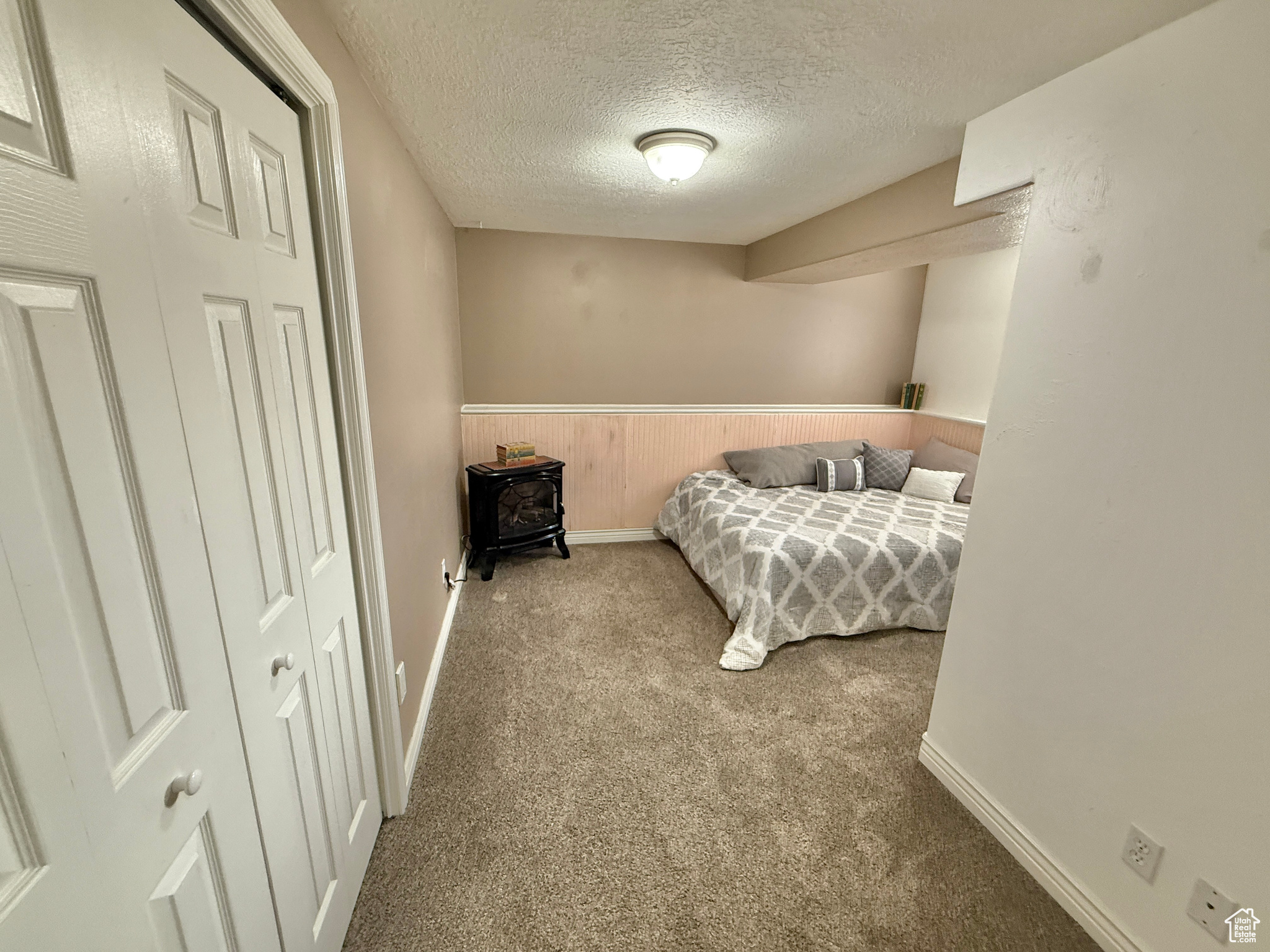Bedroom featuring a textured ceiling, light colored carpet, and a closet