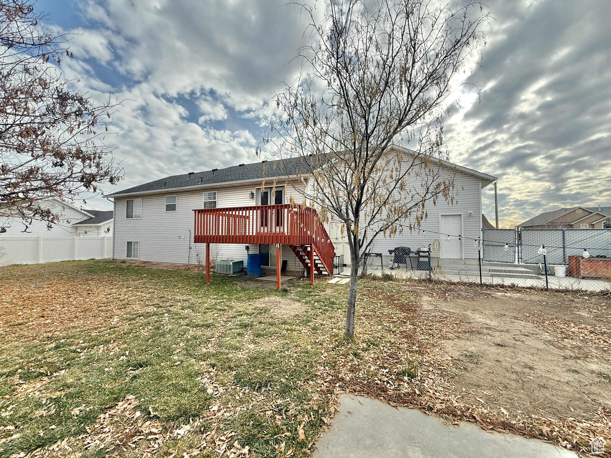 Rear view of property with central AC, a deck, and a lawn