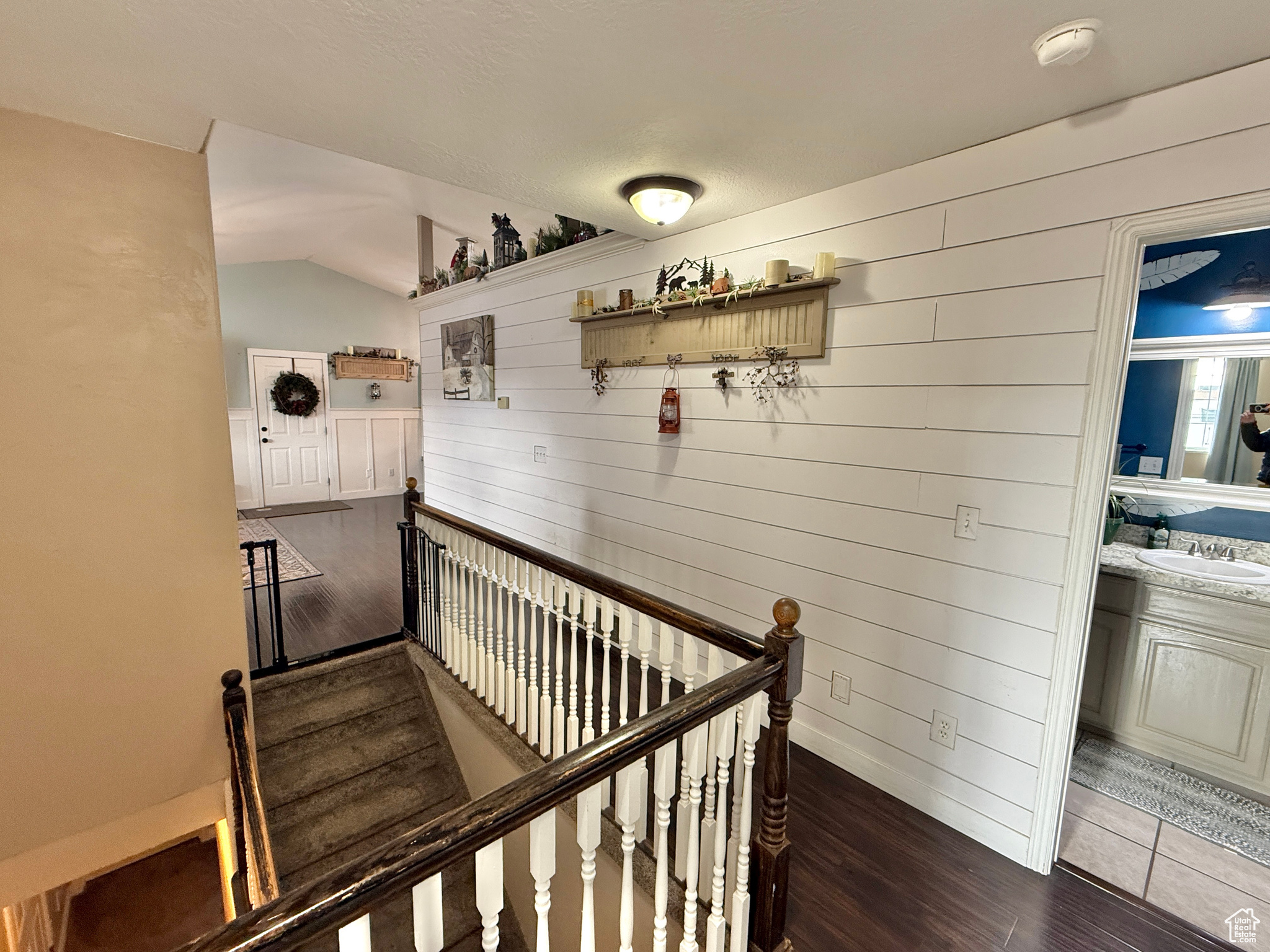 Stairway featuring wooden walls, sink, lofted ceiling, and hardwood / wood-style flooring