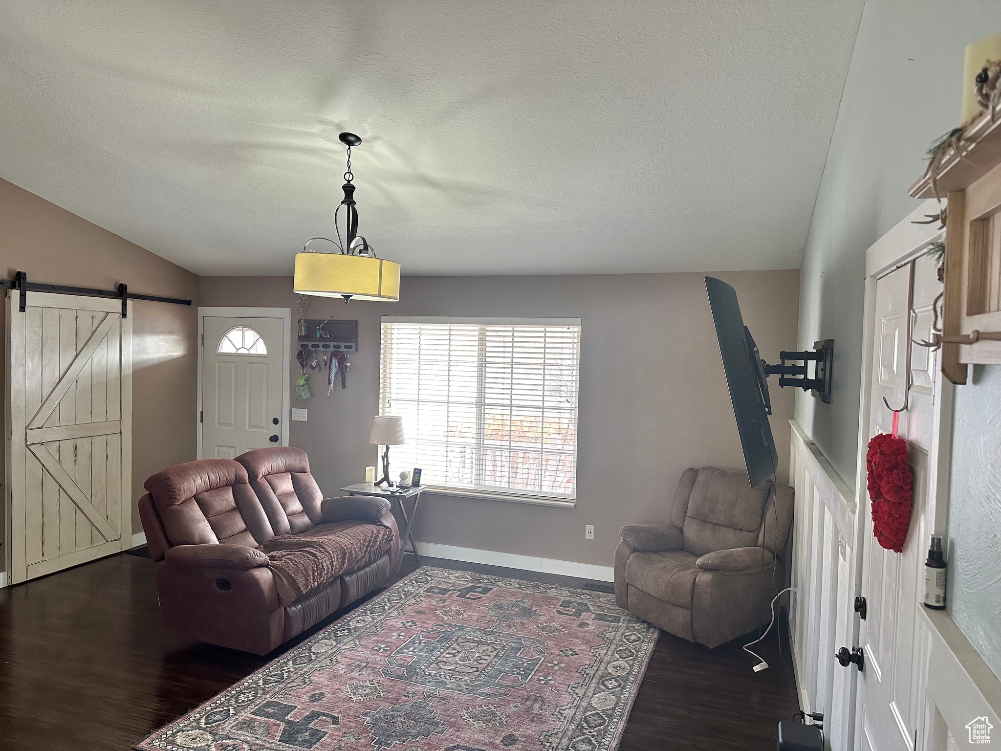 Living room with dark wood-type flooring, a barn door, and vaulted ceiling
