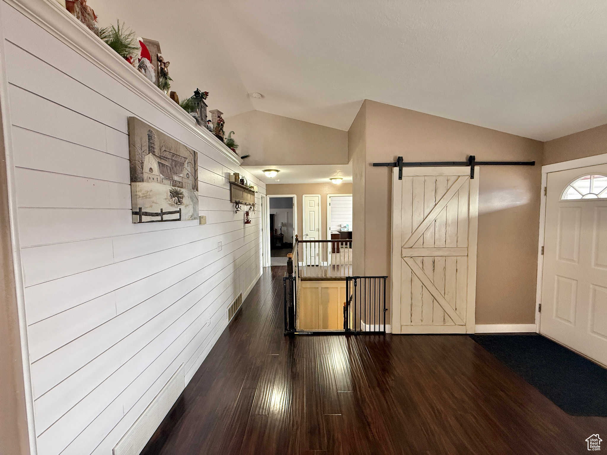 Entryway featuring a barn door, dark wood-type flooring, and vaulted ceiling