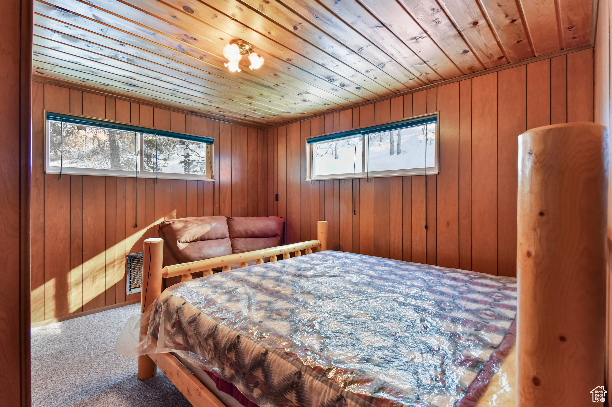 Carpeted bedroom with wooden walls and wooden ceiling