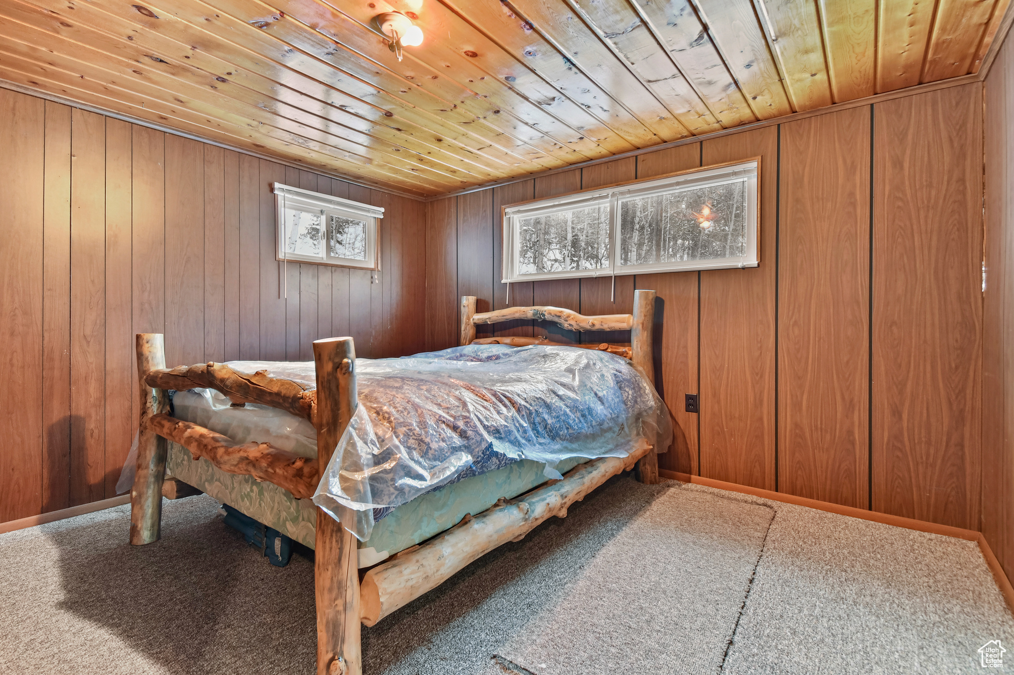 Bedroom featuring wood walls, wood ceiling, and carpet floors