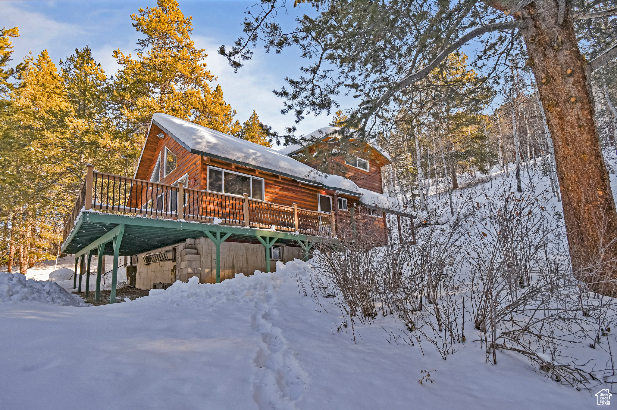 Snow covered back of property with a wooden deck