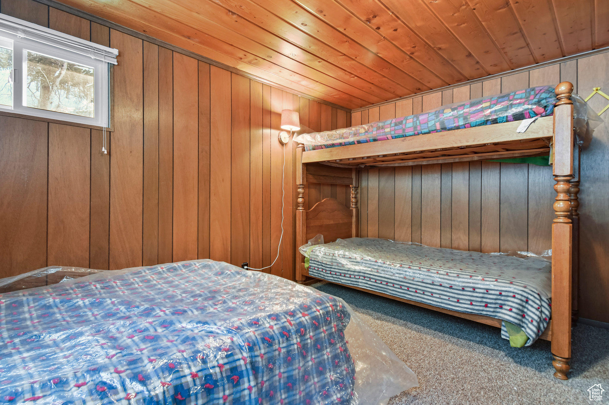 Bedroom with carpet flooring, wooden ceiling, and wooden walls
