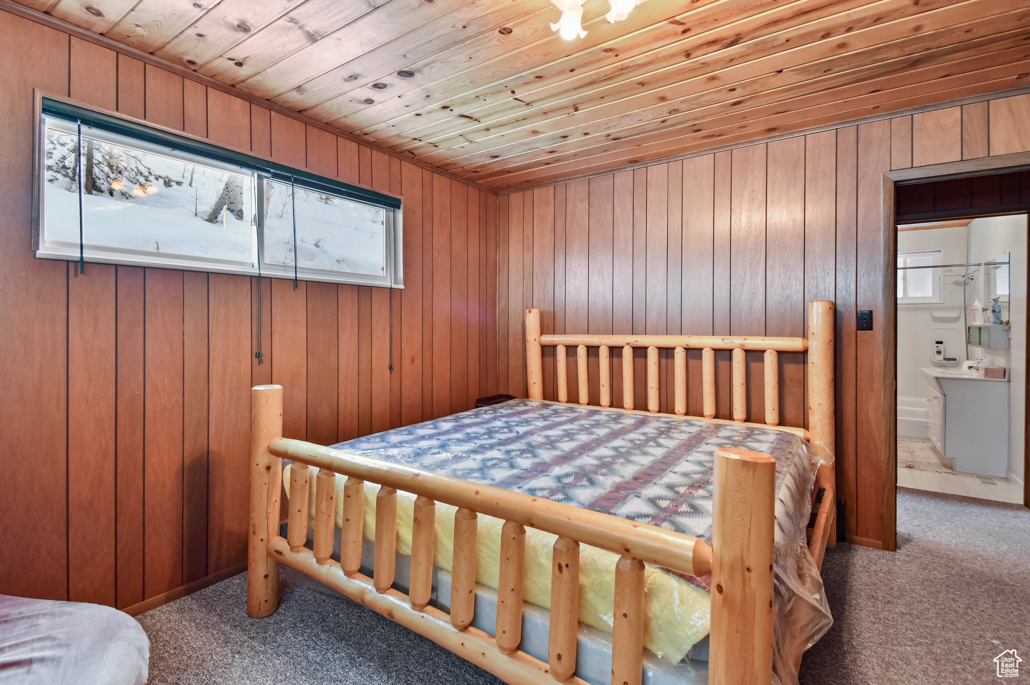 Carpeted bedroom featuring connected bathroom, wooden ceiling, and wood walls