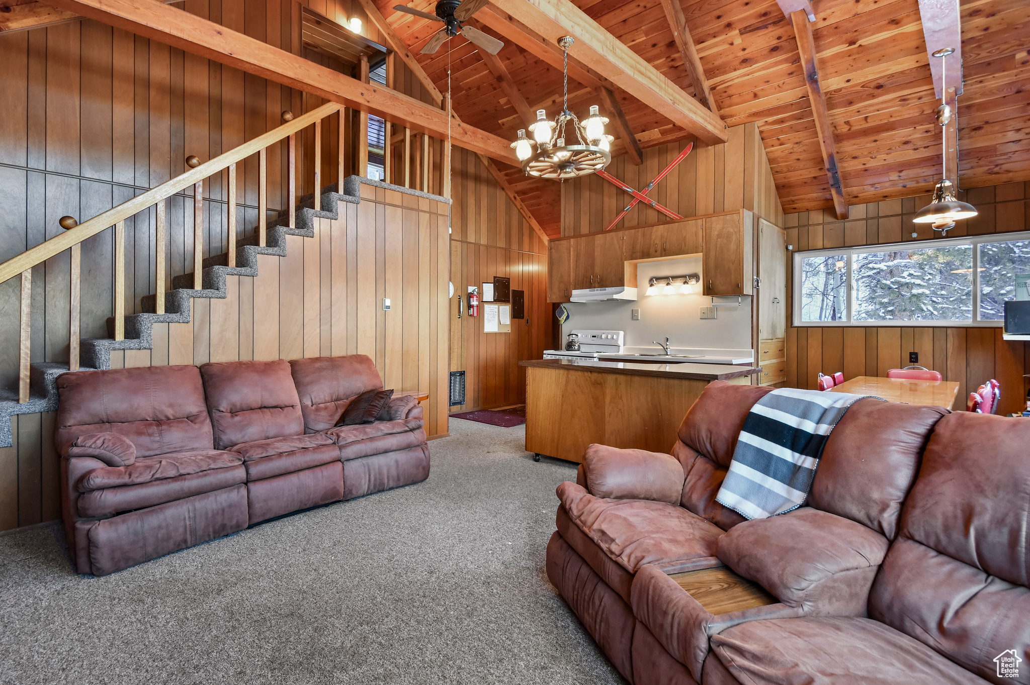 Living room with carpet, wooden walls, beamed ceiling, and wooden ceiling