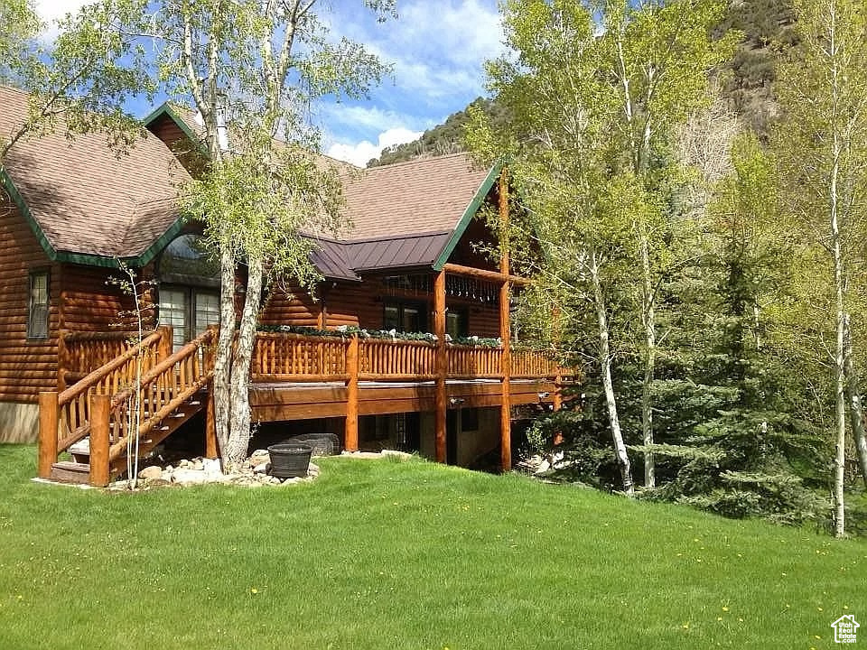 Rear view of house with a lawn and a wooden deck