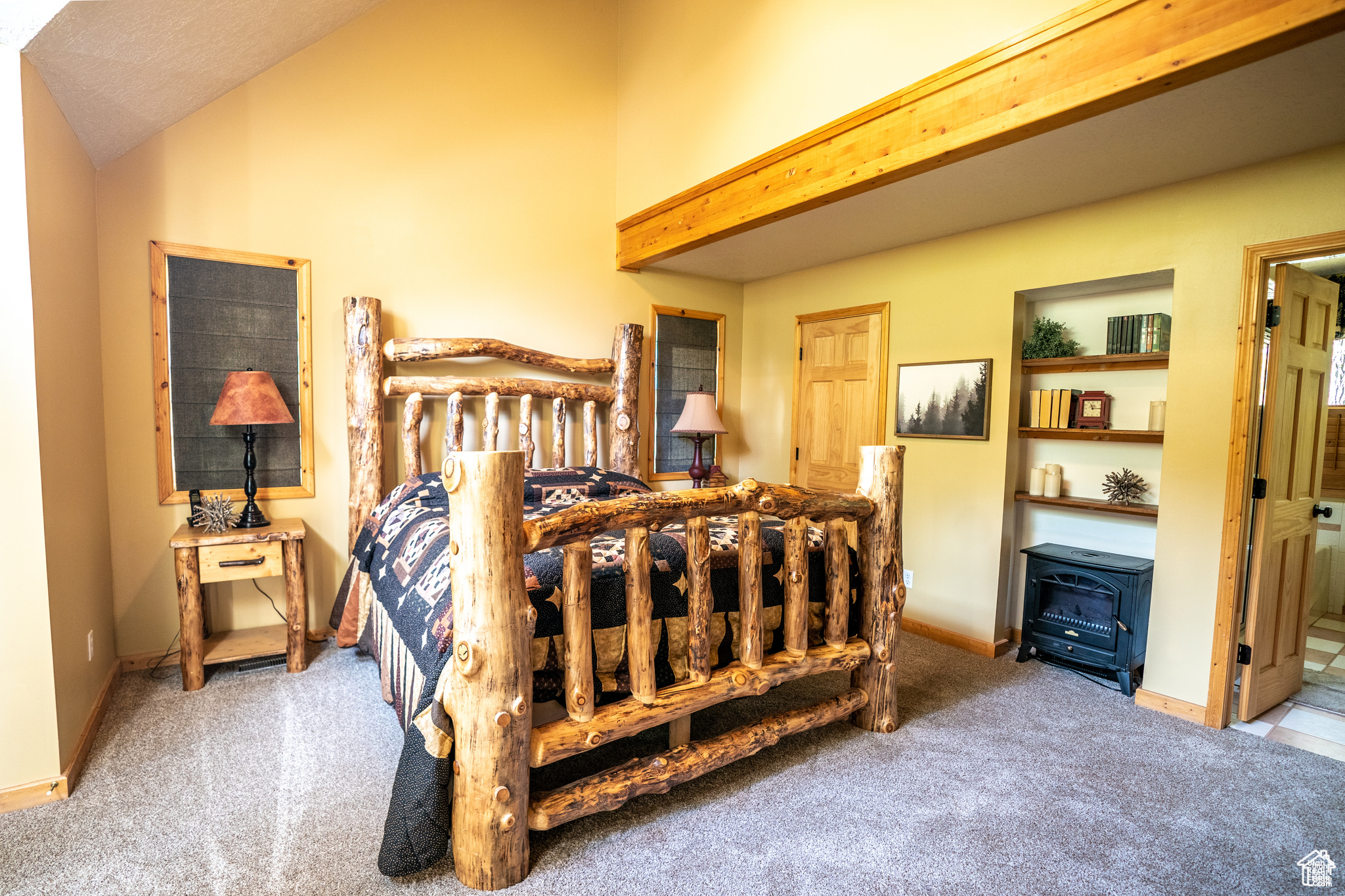 Bedroom featuring ensuite bath, carpet, and lofted ceiling