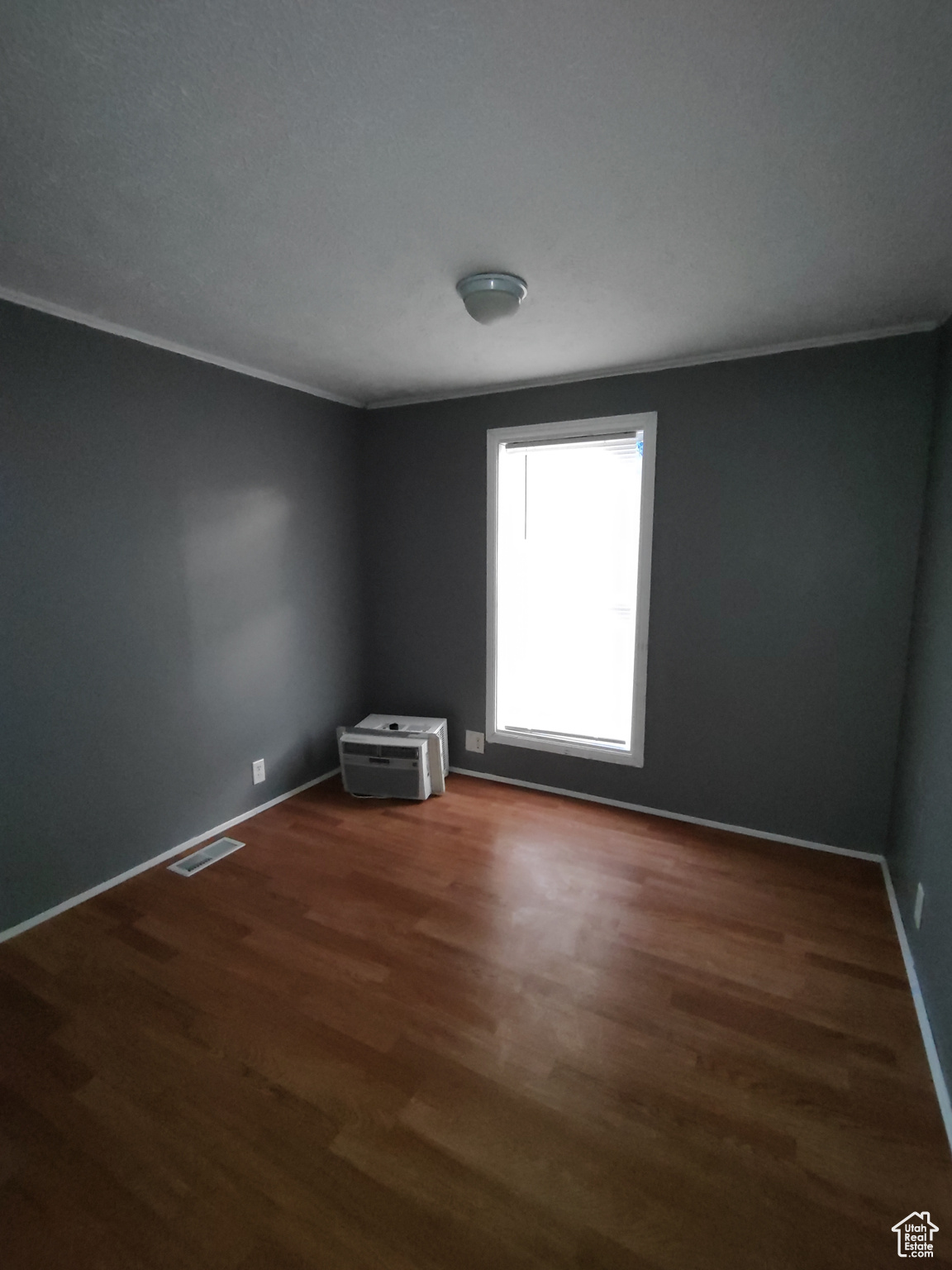 Unfurnished room featuring dark hardwood / wood-style flooring and ornamental molding