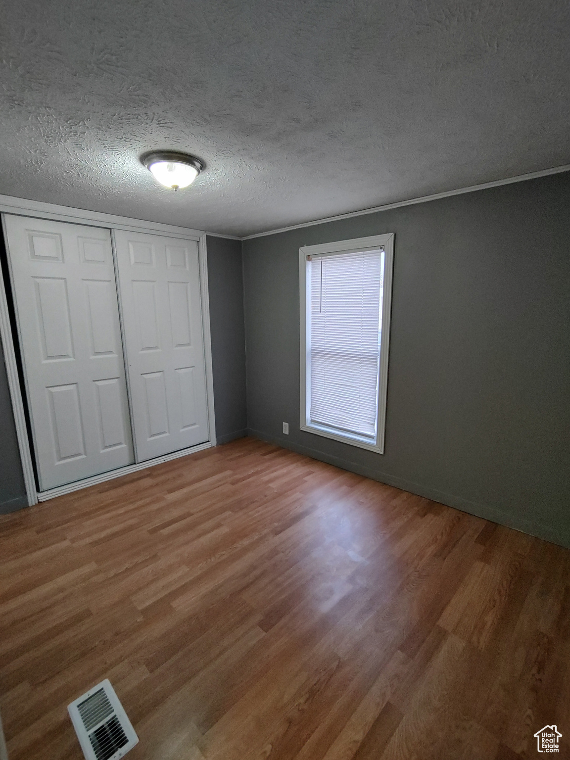 Unfurnished bedroom featuring hardwood / wood-style floors, a textured ceiling, and a closet