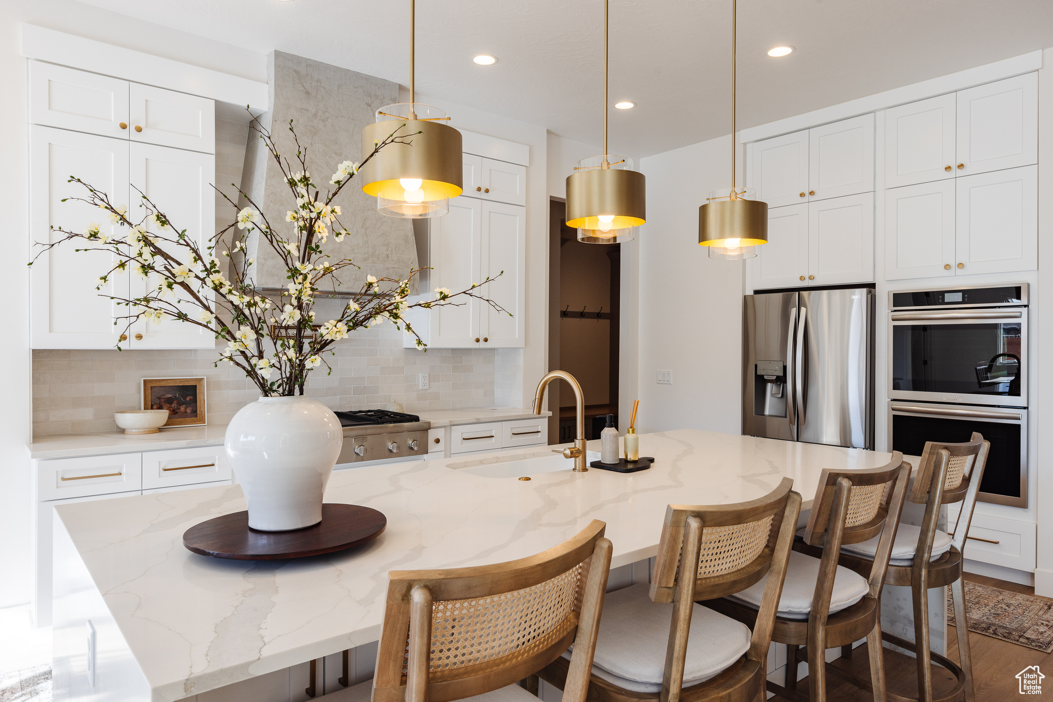 Kitchen with a kitchen island with sink, stainless steel fridge with ice dispenser, sink, and double oven
