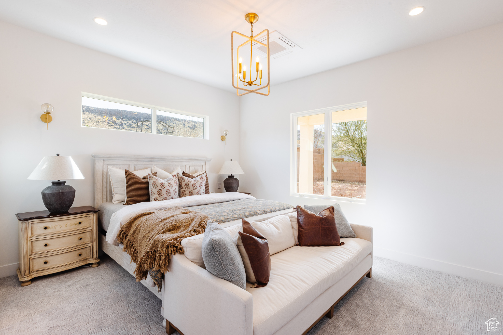 Carpeted bedroom with an inviting chandelier
