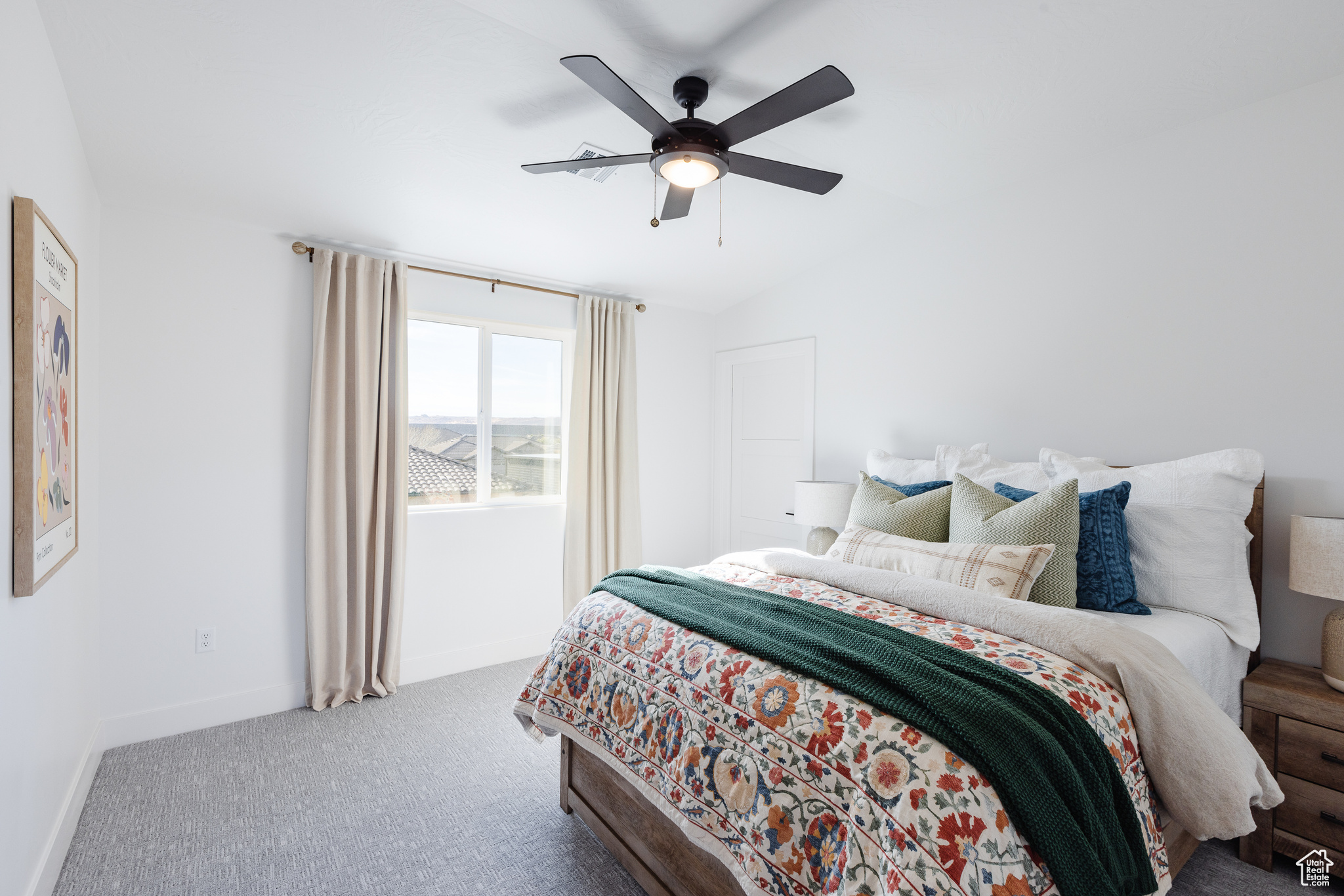 Carpeted bedroom with ceiling fan and vaulted ceiling