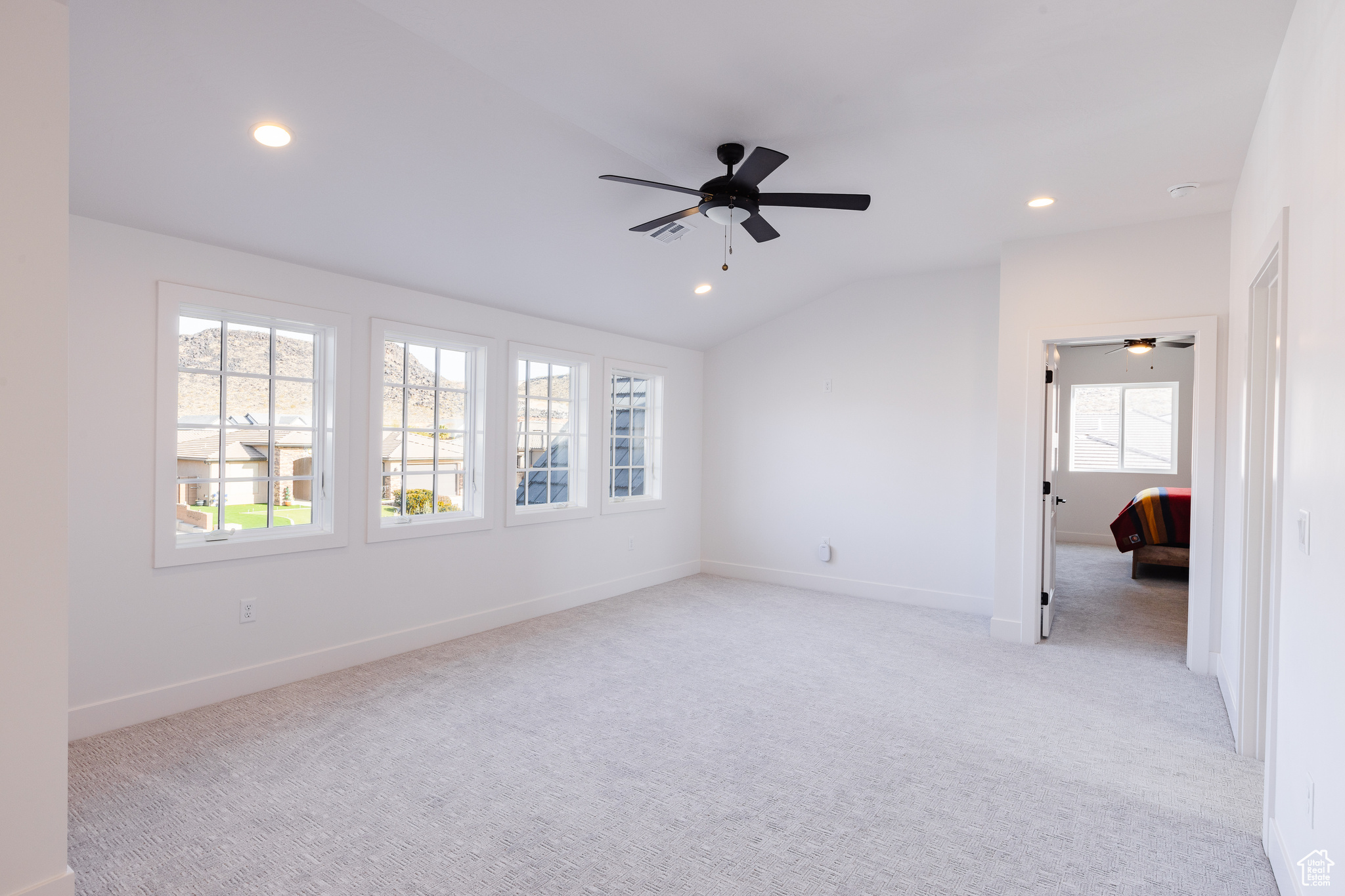 Empty room with light colored carpet and vaulted ceiling