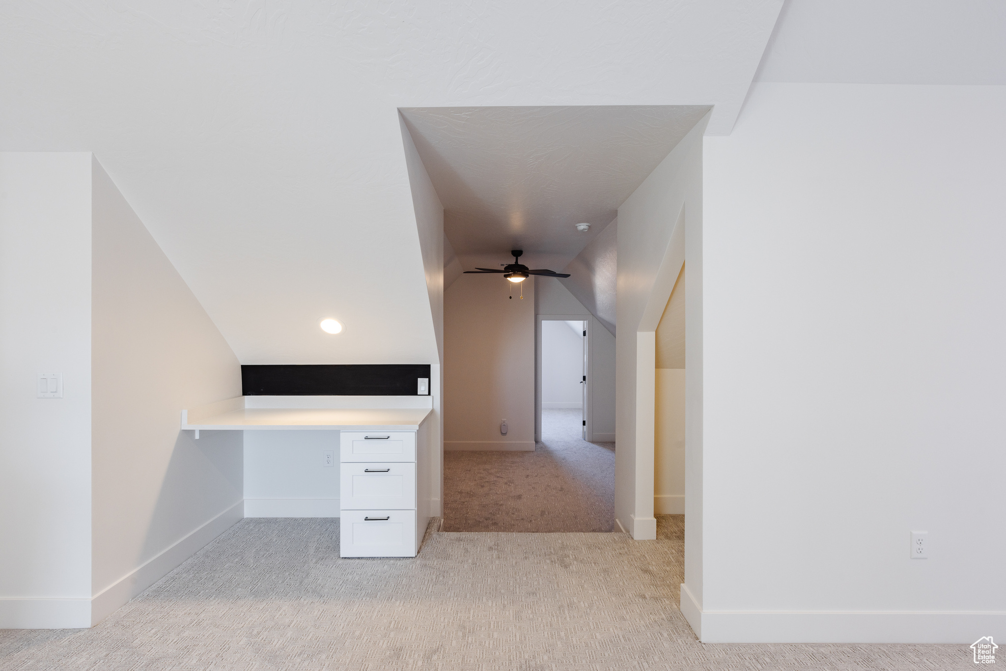 Interior space with ceiling fan, light colored carpet, and lofted ceiling