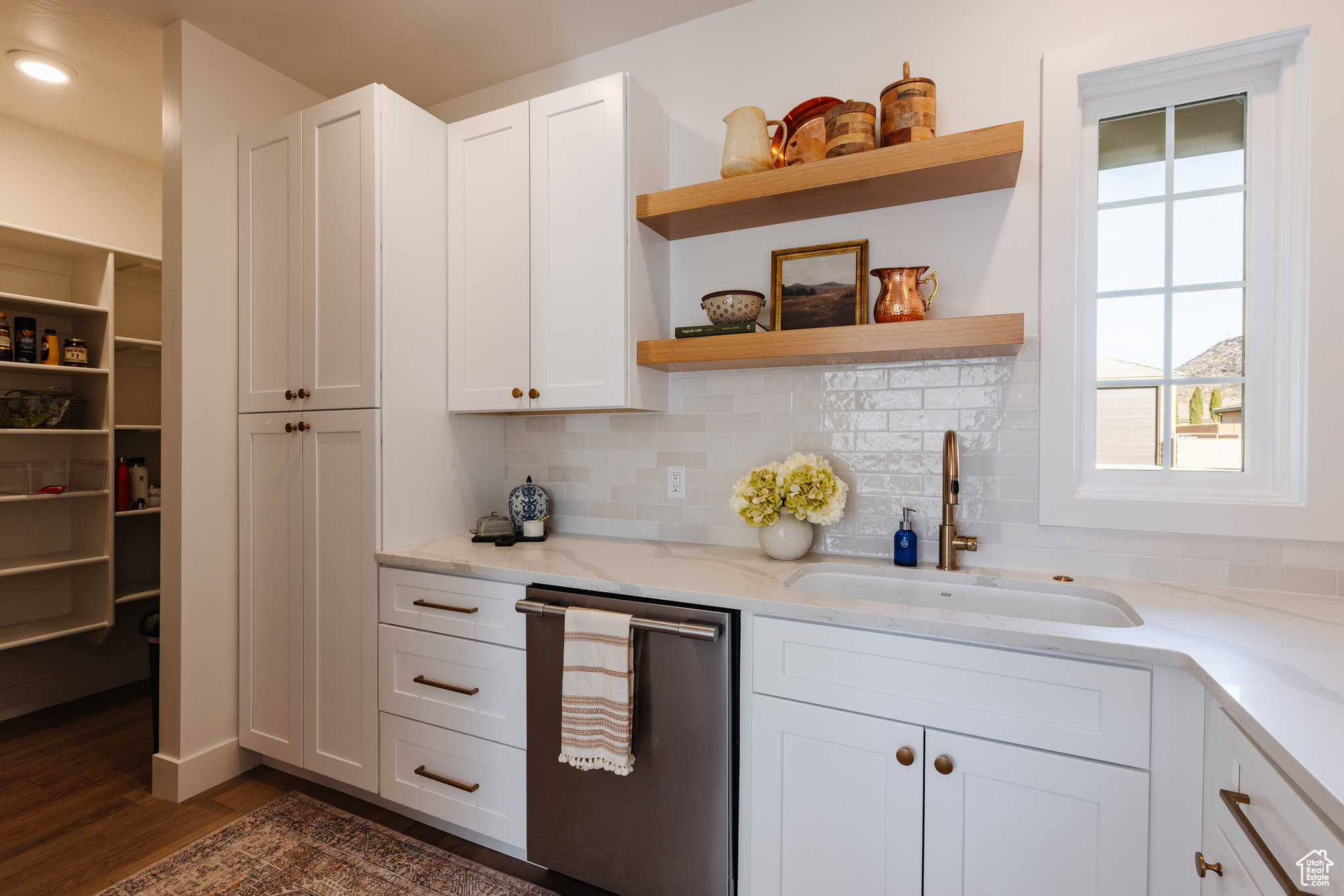 Kitchen featuring light stone countertops, sink, and white cabinets