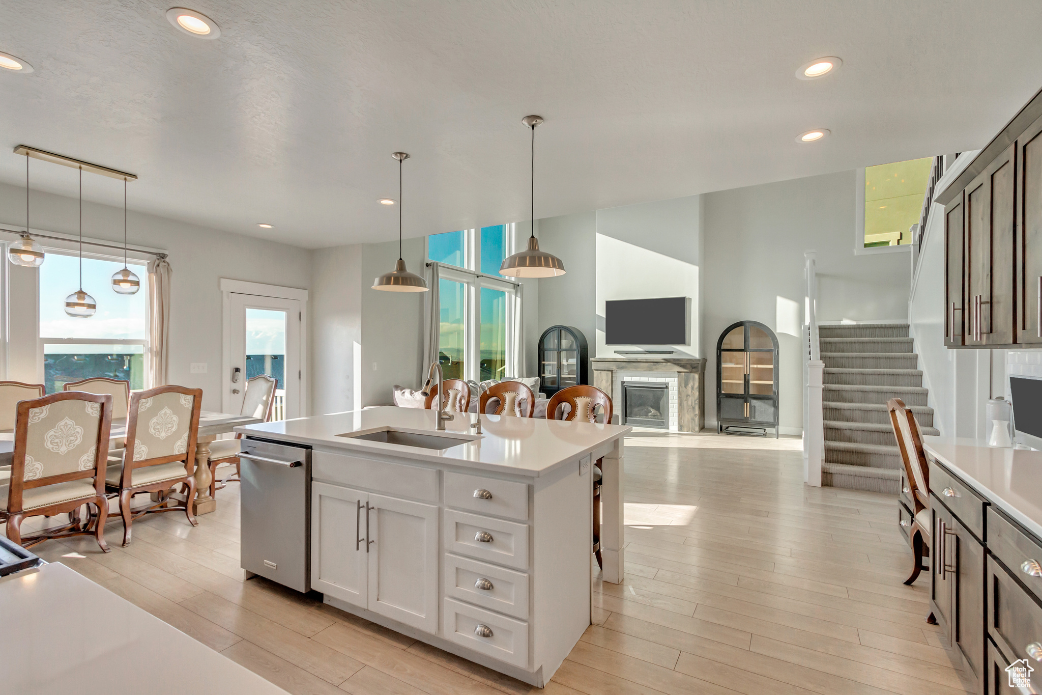 Kitchen with sink, a center island with sink, white cabinets, and hanging light fixtures