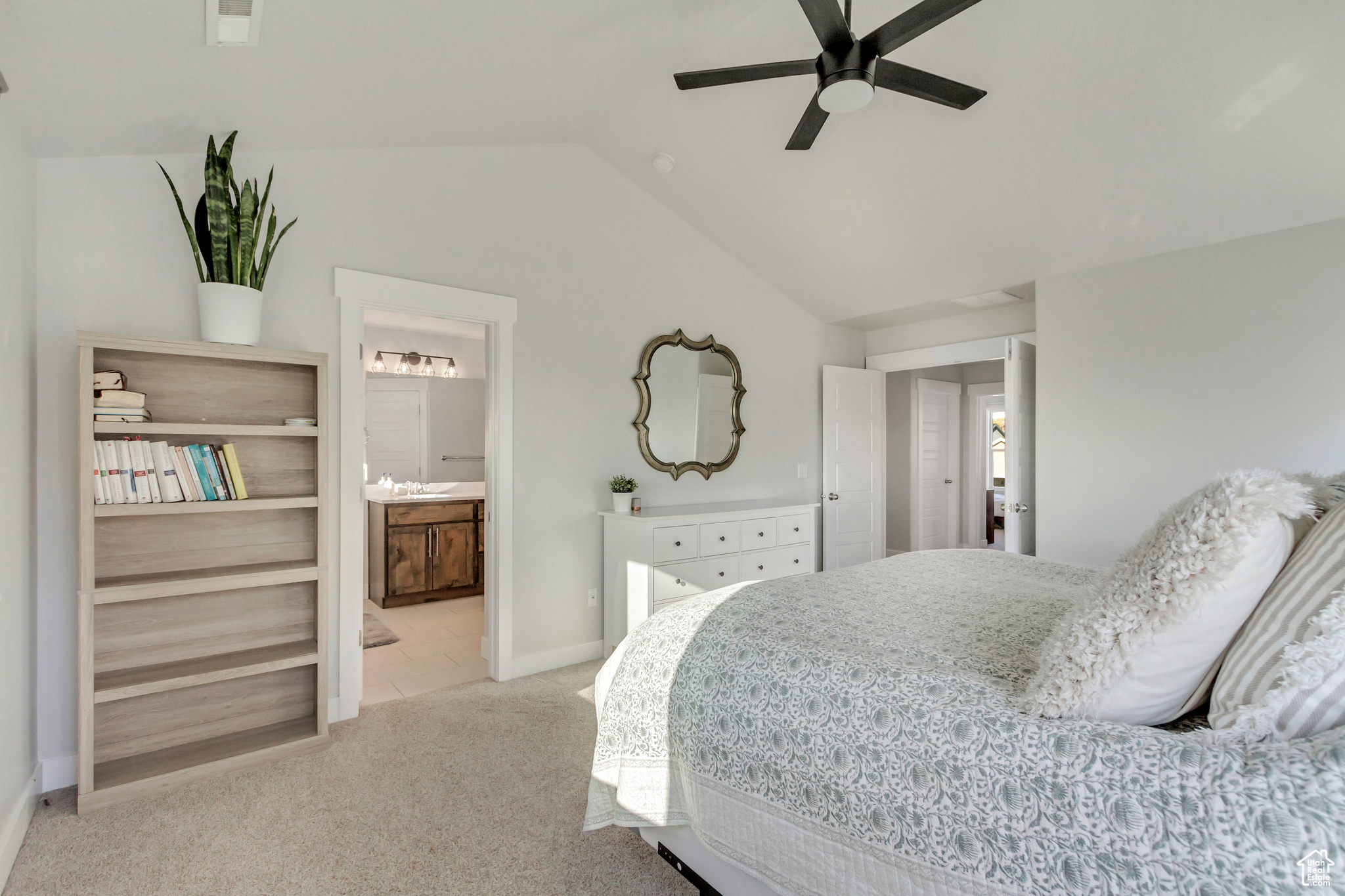 Carpeted bedroom featuring lofted ceiling, ensuite bathroom, sink, and ceiling fan