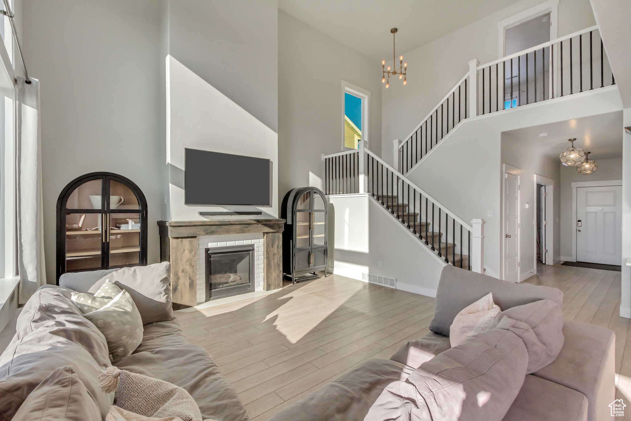 Living room featuring a towering ceiling, an inviting chandelier, light wood-type flooring, and plenty of natural light