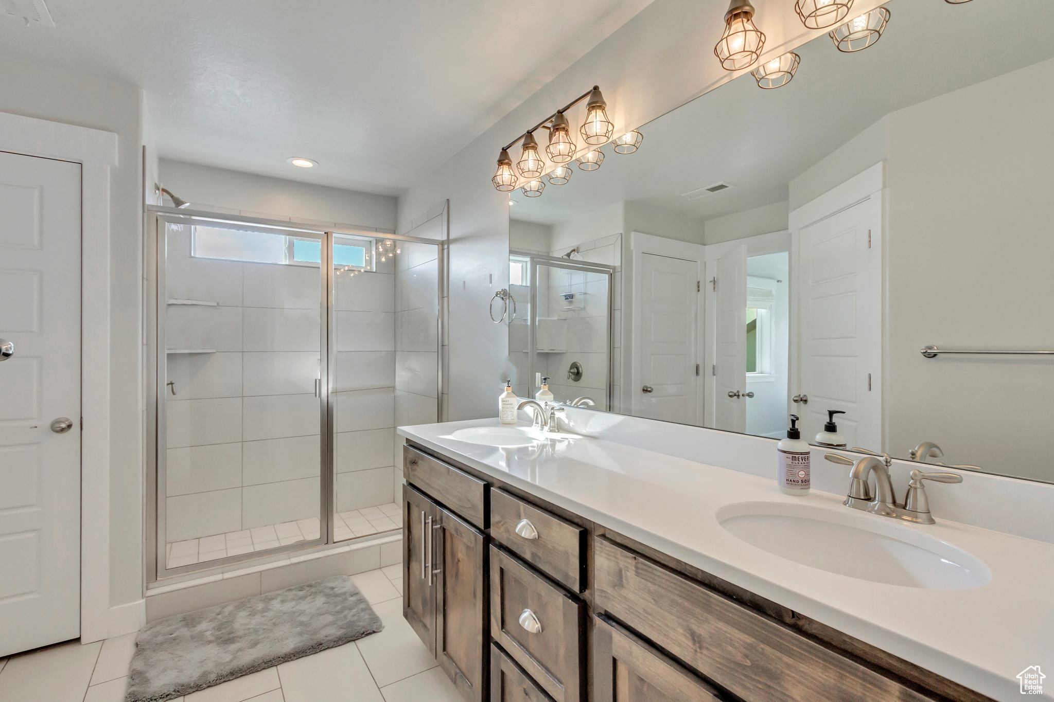 Bathroom with an enclosed shower, tile patterned floors, and vanity