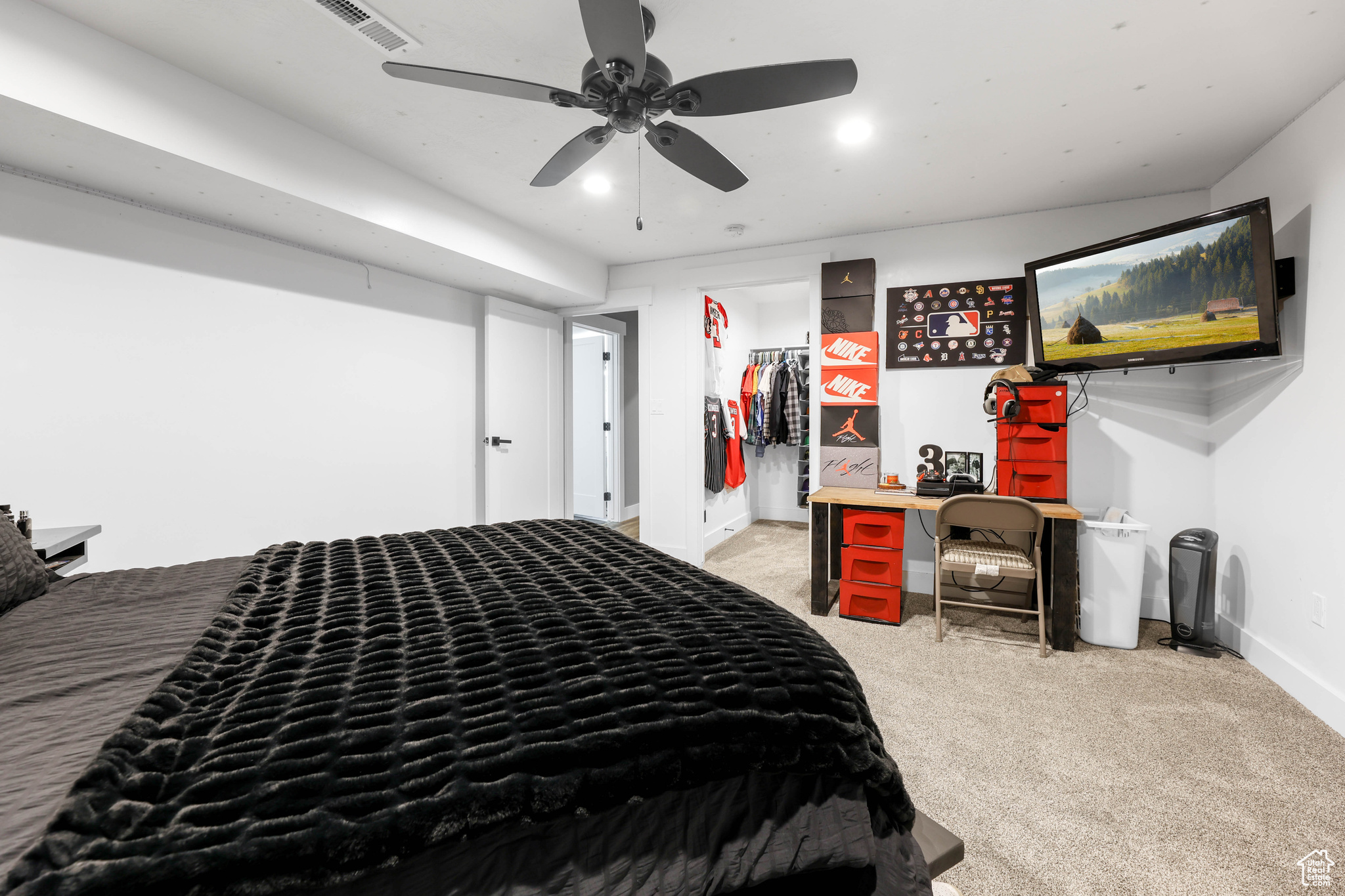 Carpeted bedroom with a walk in closet, ceiling fan, and a closet