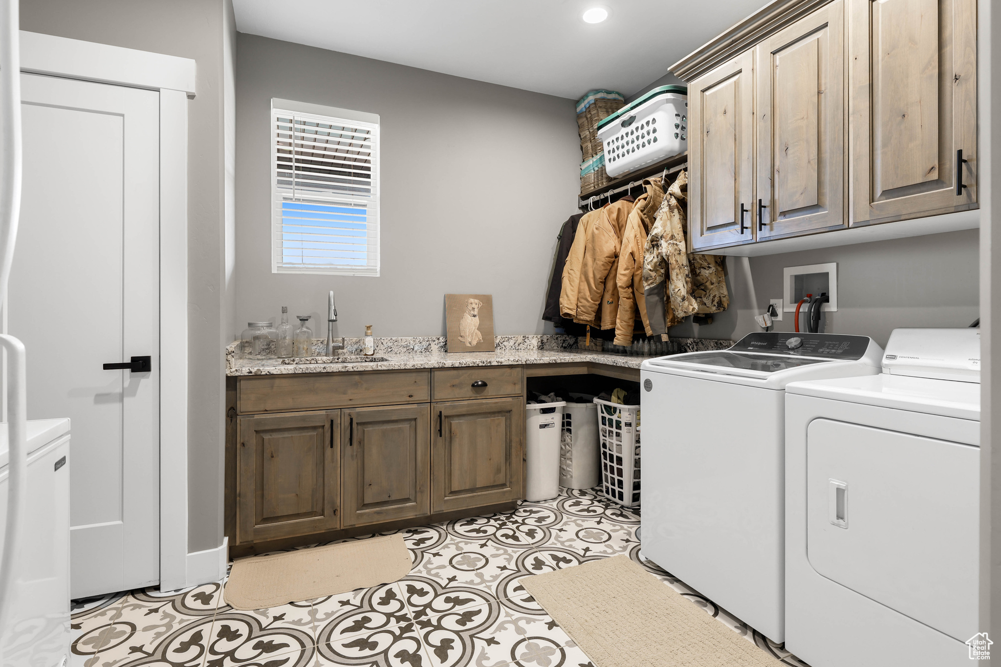 Laundry room with sink, light tile patterned floors, cabinets, and independent washer and dryer