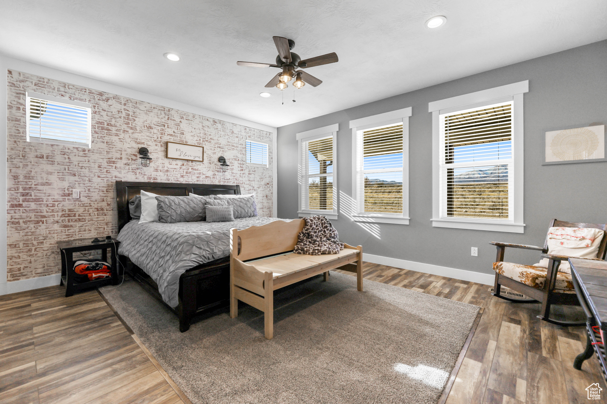 Bedroom featuring ceiling fan, brick wall, and hardwood / wood-style flooring