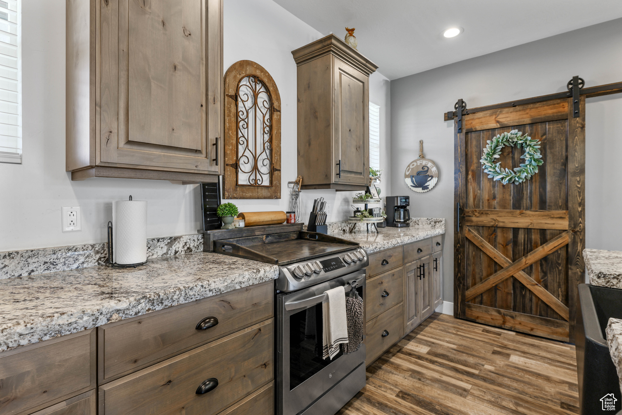 Kitchen with a barn door, light stone counters, electric stove, and dark hardwood / wood-style floors