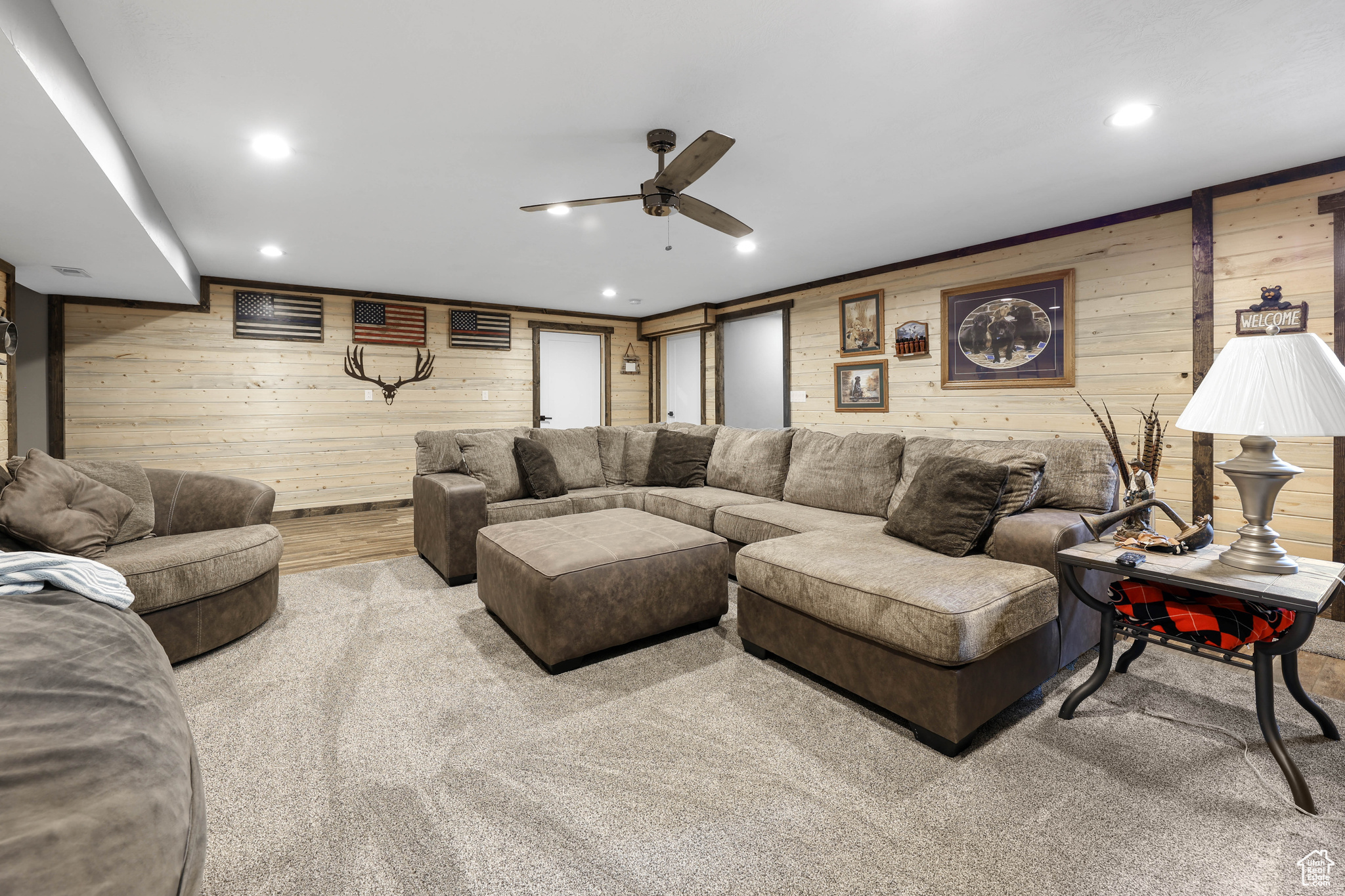 Carpeted living room featuring wood walls and ceiling fan