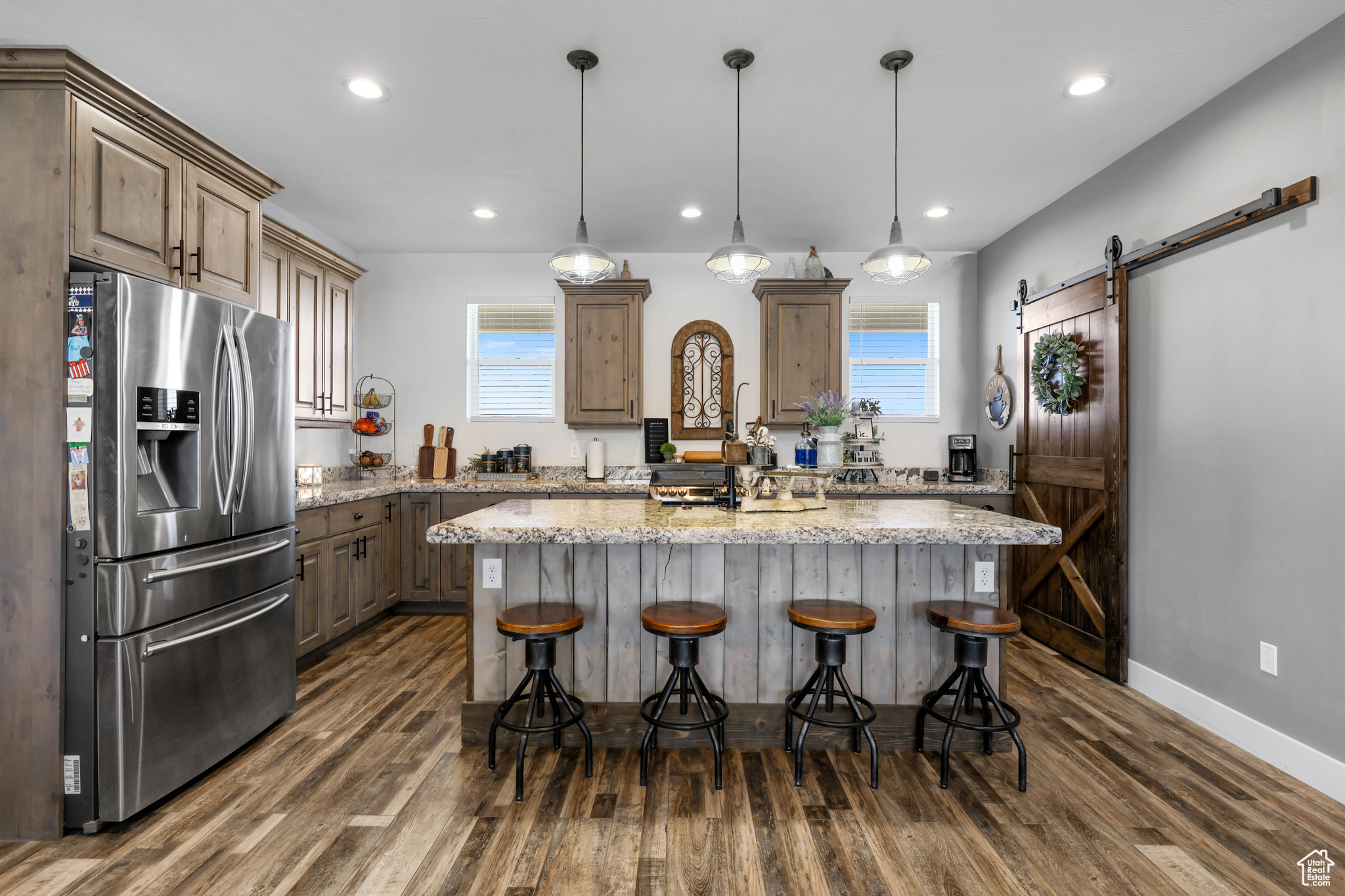 Kitchen featuring a center island, a kitchen breakfast bar, stainless steel fridge, a barn door, and light stone countertops