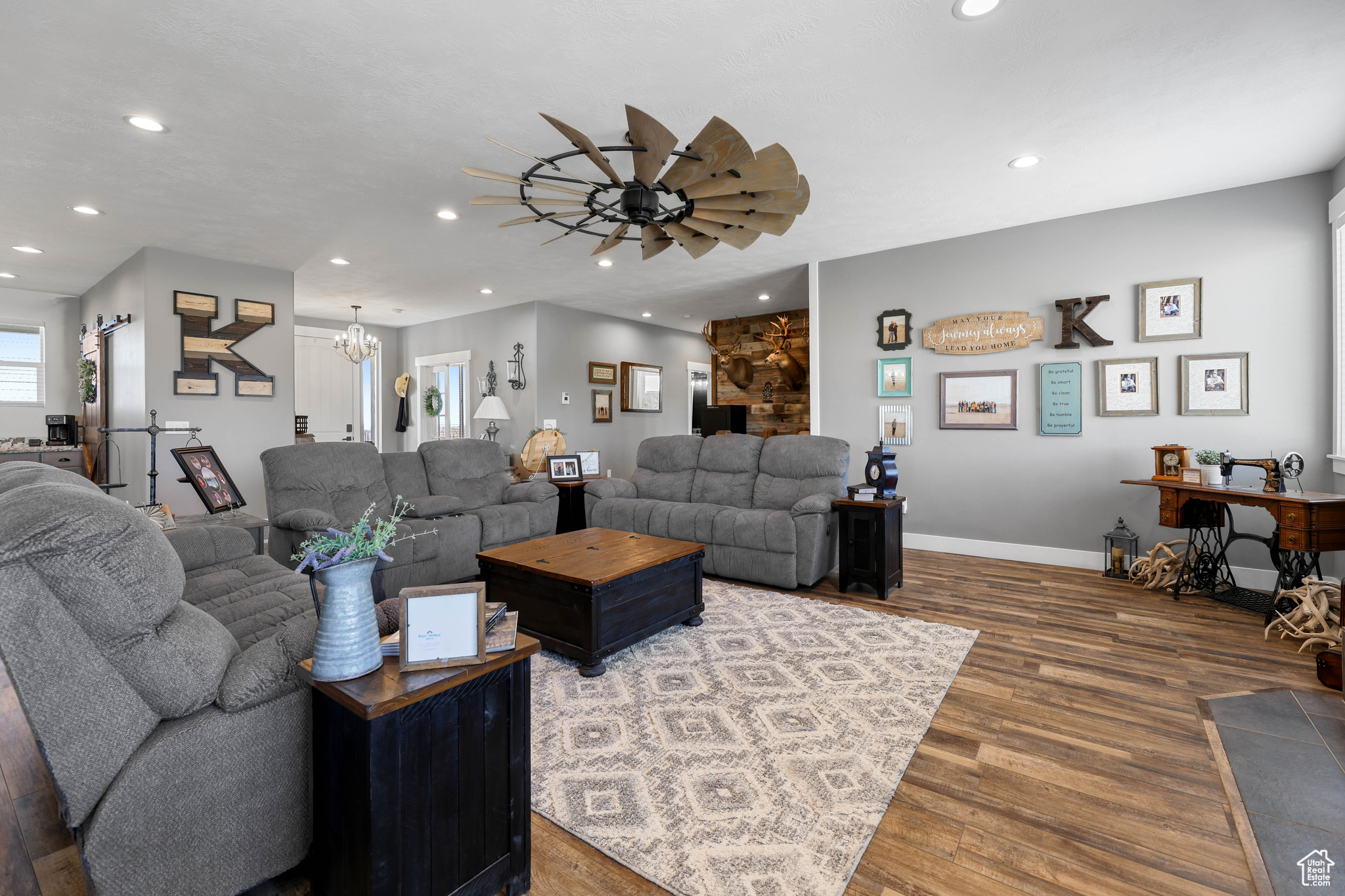 Living room with wood-type flooring and ceiling fan with notable chandelier
