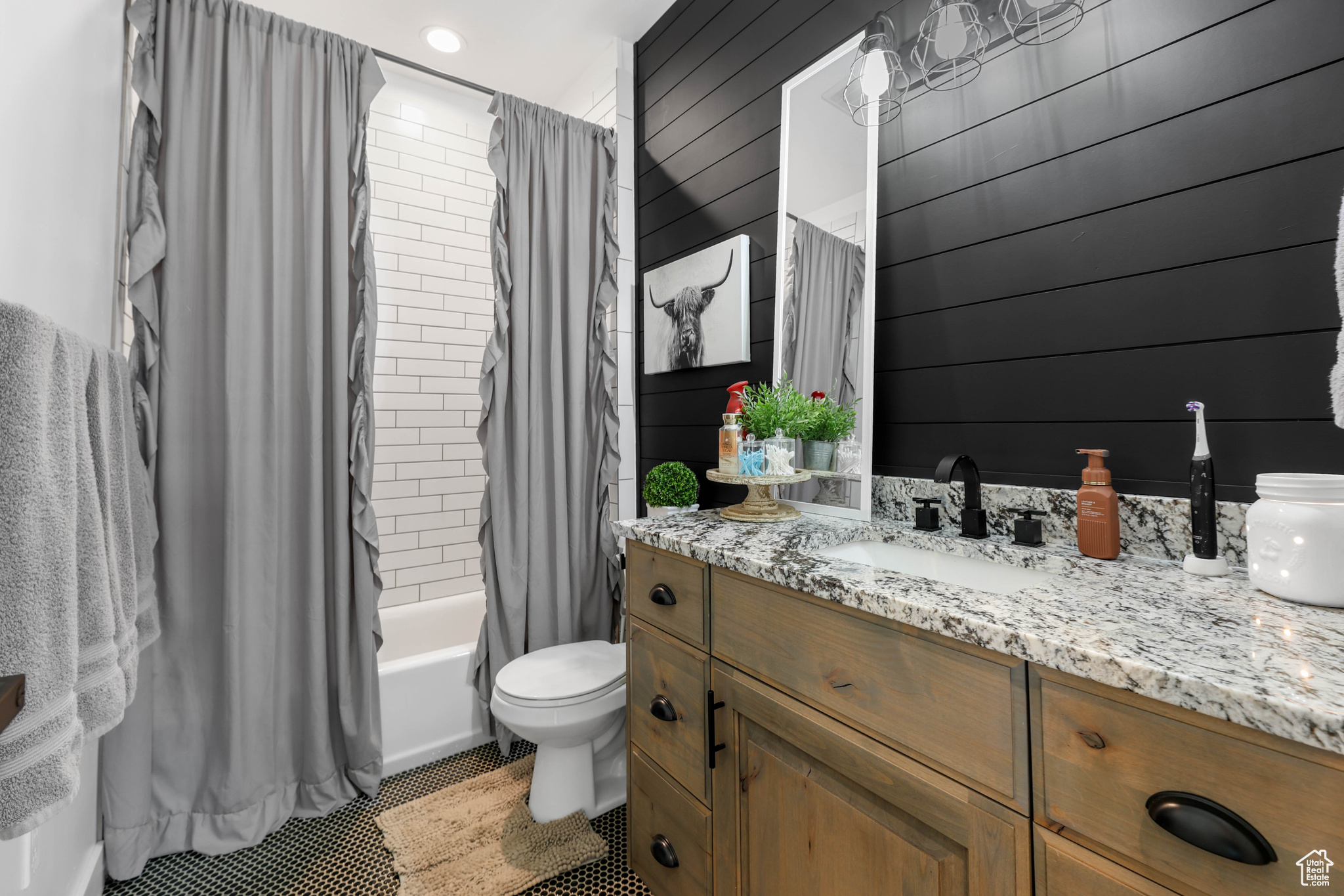 Full bathroom featuring tile patterned floors, toilet, wooden walls, shower / bath combo with shower curtain, and vanity