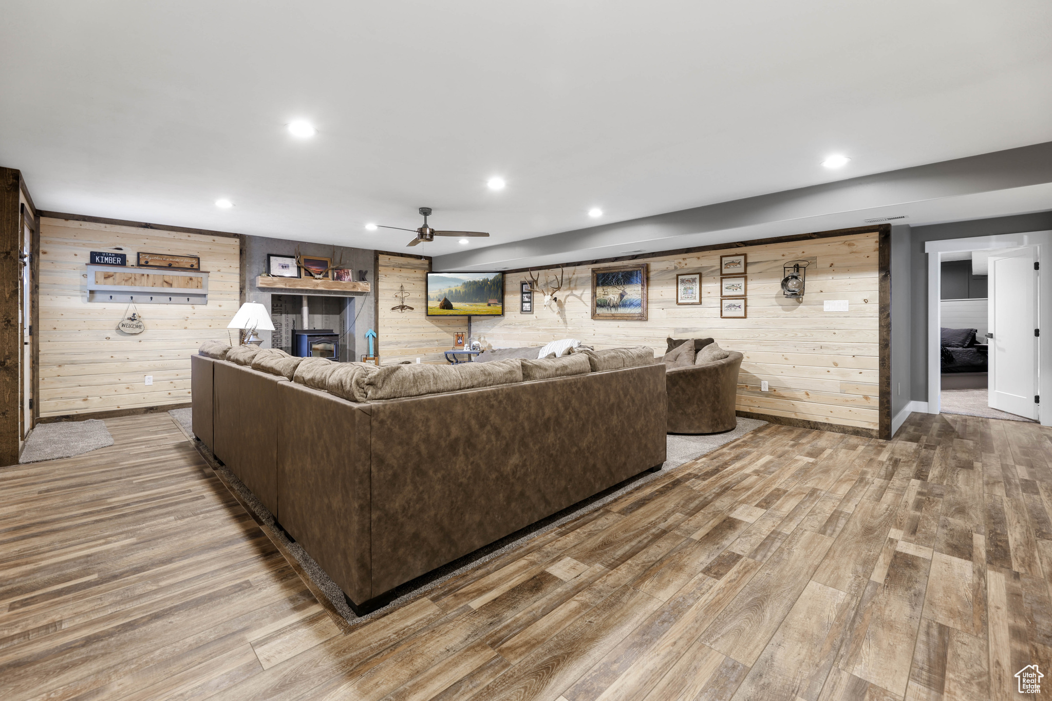 Living room with hardwood / wood-style flooring, ceiling fan, and wooden walls