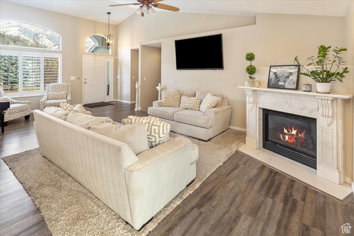 Living room featuring LPV -style flooring, ceiling fan, lofted ceiling, and a fireplace