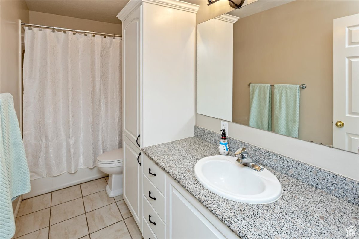 Main floor full bathroom with tile patterned flooring, shower / tub combo, vanity, and toilet