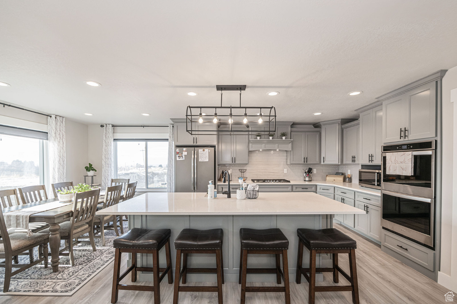 Kitchen featuring stainless steel appliances, gray cabinetry, and an island with sink