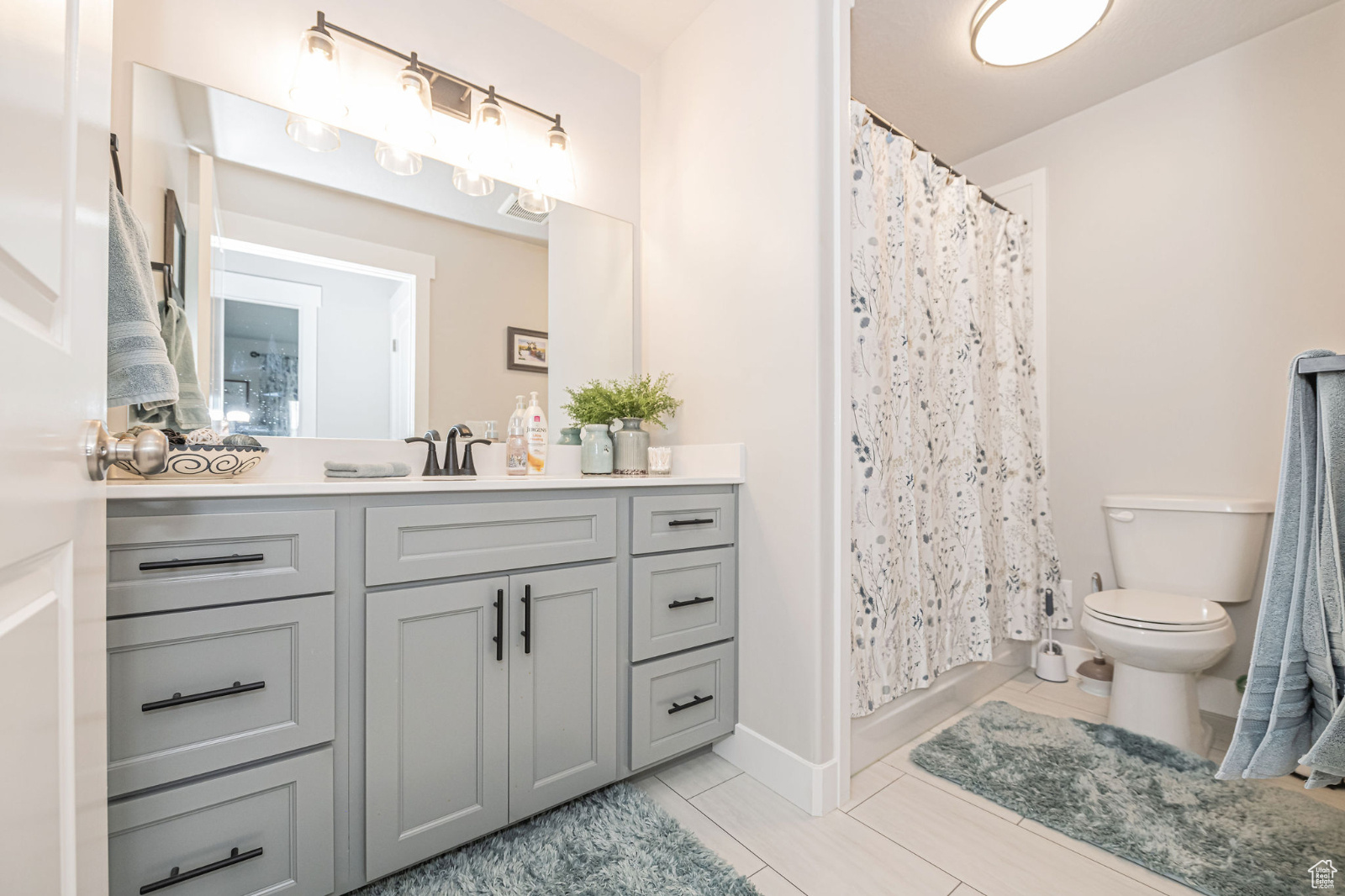Bathroom featuring tile flooring, vanity, toilet, and a shower with shower curtain